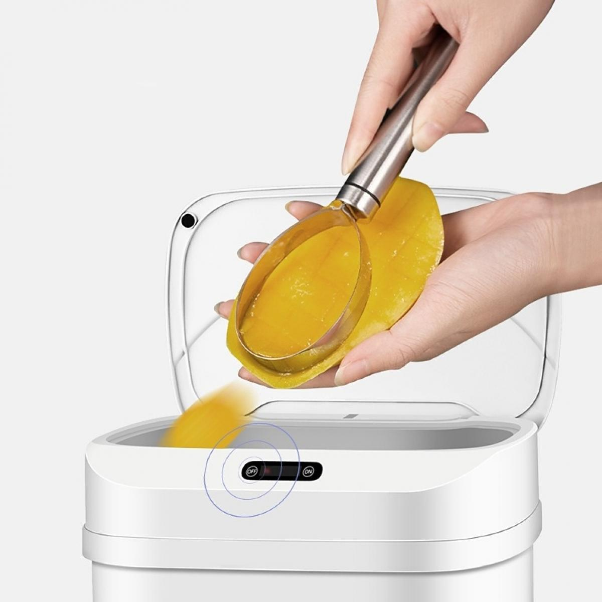 Eine Person schöpft Mangoscheiben mit einem Werkzeug. Die Mango wird in einen weißen Mülleimer gelegt. Die Dose hat eine Ein-/Aus-Taste.