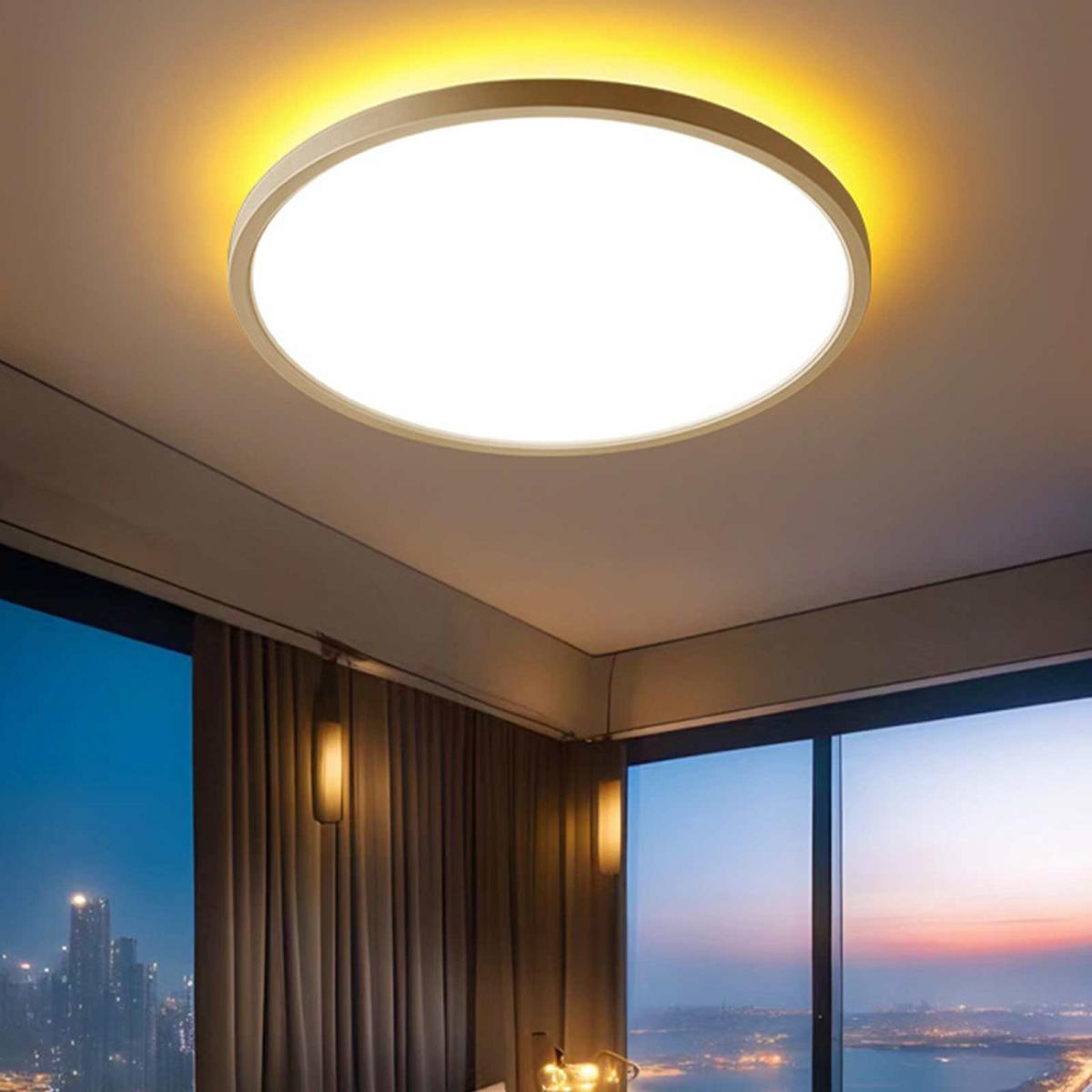 Eine helle, runde Deckenleuchte beleuchtet einen Raum. Große Fenster zeigen eine Skyline und Vorhänge. Zwei Lampen sind sichtbar.