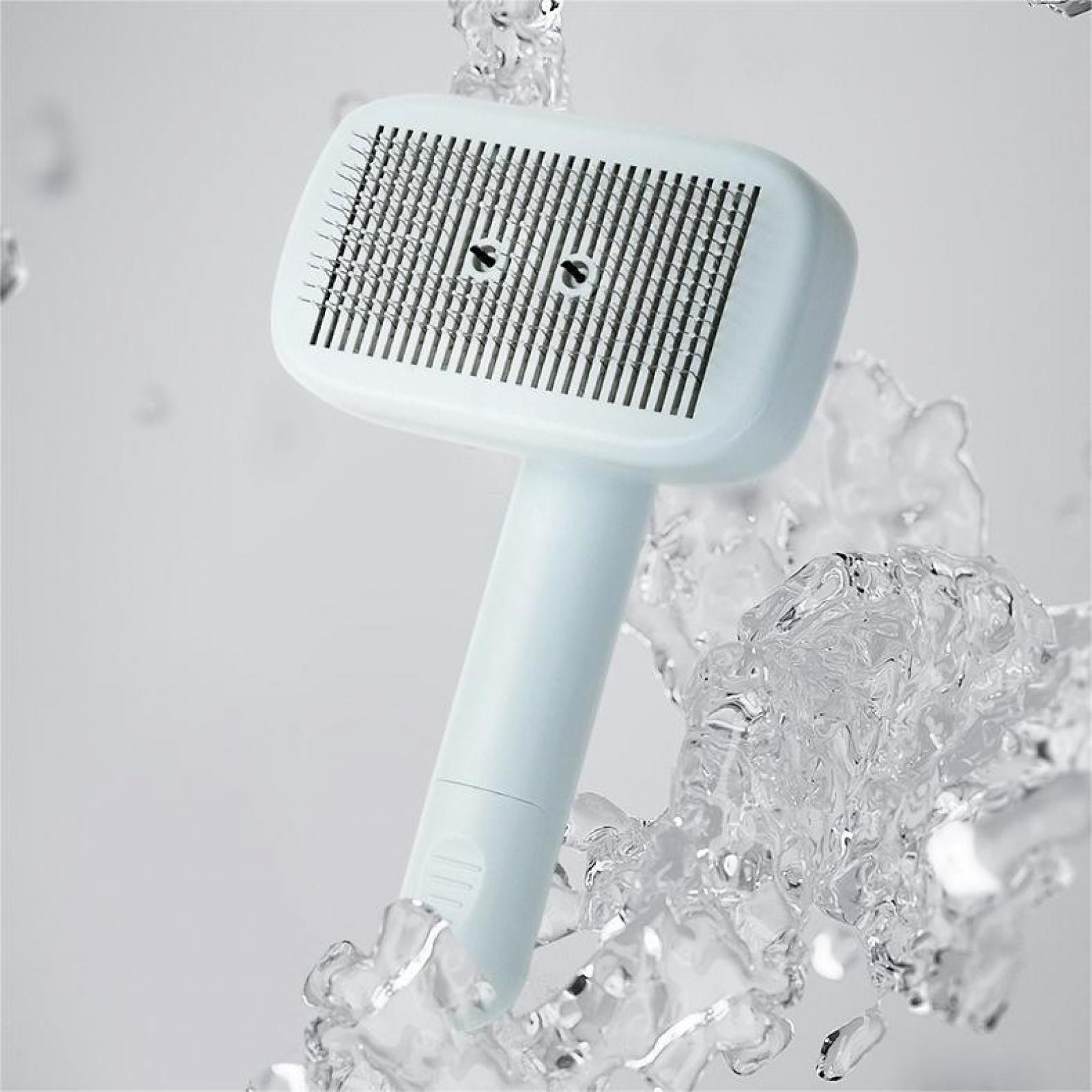 Eine blaue Haustierbürste mit Metallzähnen, umgeben von Wassertropfen, auf weißem Hintergrund.