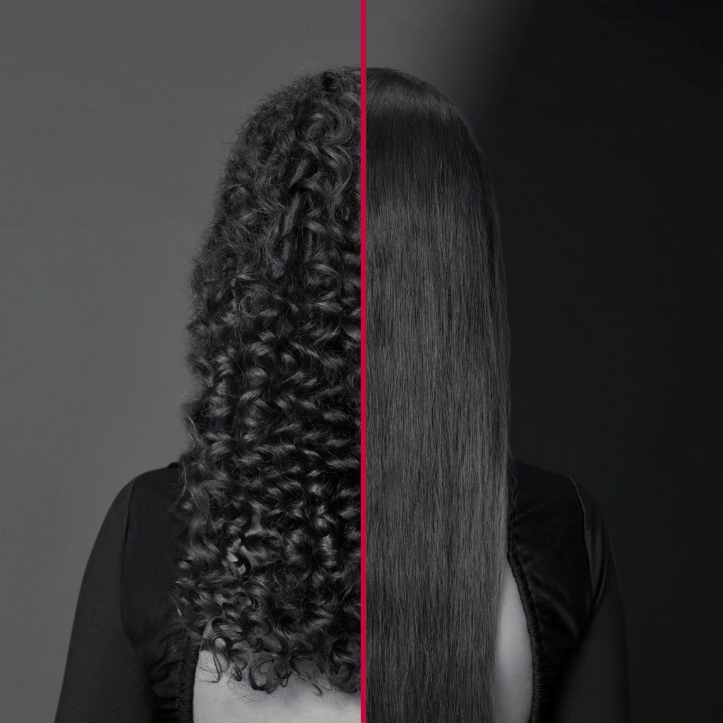 Obraz przedstawia włosy kobiety podzielone czerwoną linią. Jedna strona ma kręcone włosy, druga proste. Tło jest ciemnoszare.