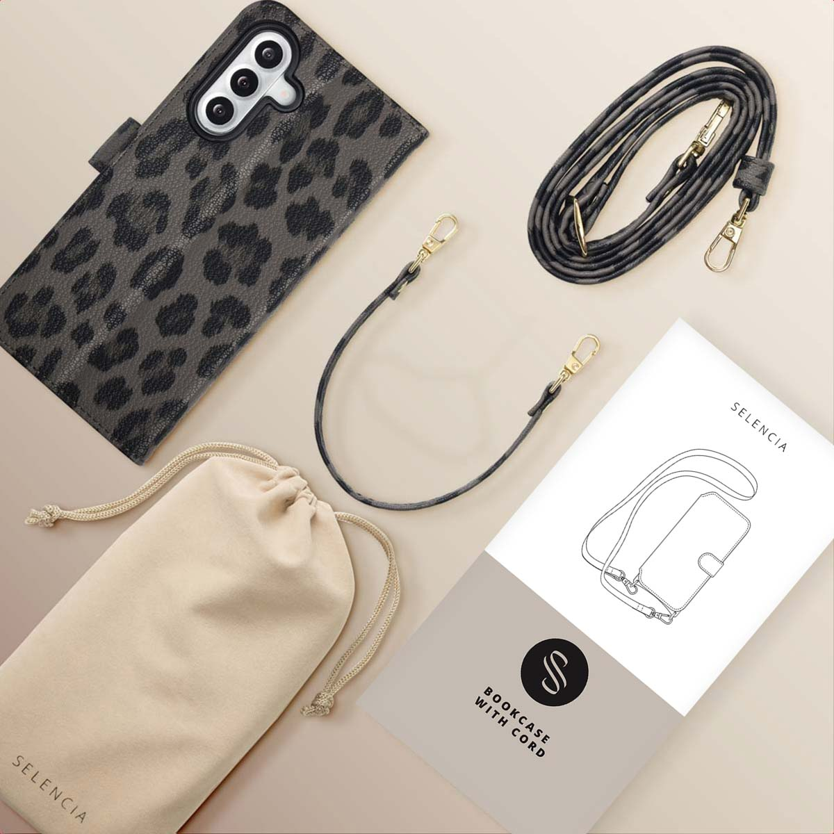Un étui de téléphone à imprimé léopard, une bandoulière, une pochette et un livret sont disposés sur une surface beige.