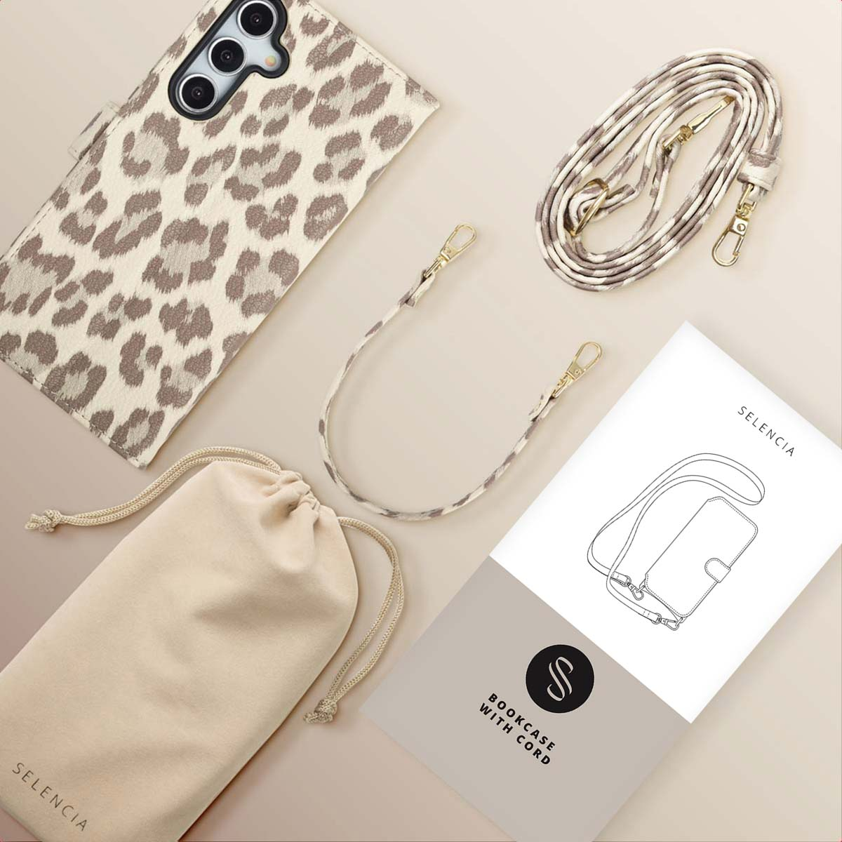 Un étui de téléphone avec un imprimé léopard, une sangle assortie, un sac à cordon et un manuel d'instructions sur une surface beige.