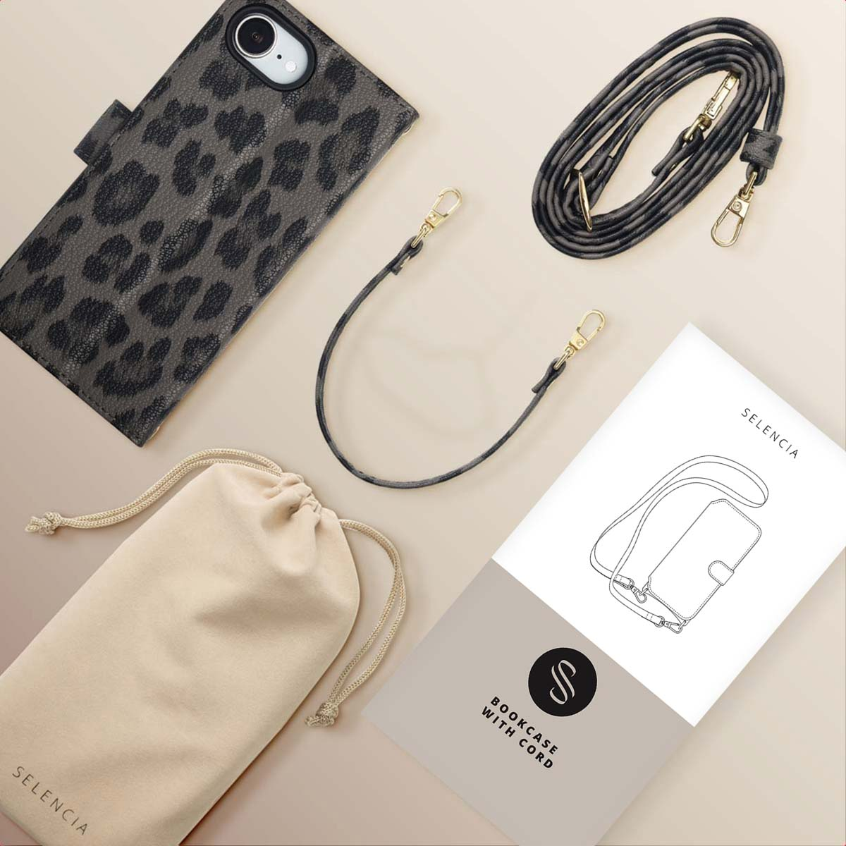 Coque de téléphone à imprimé léopard, sangle grise, sac beige et livret sur une surface claire. Accessoires disposés.