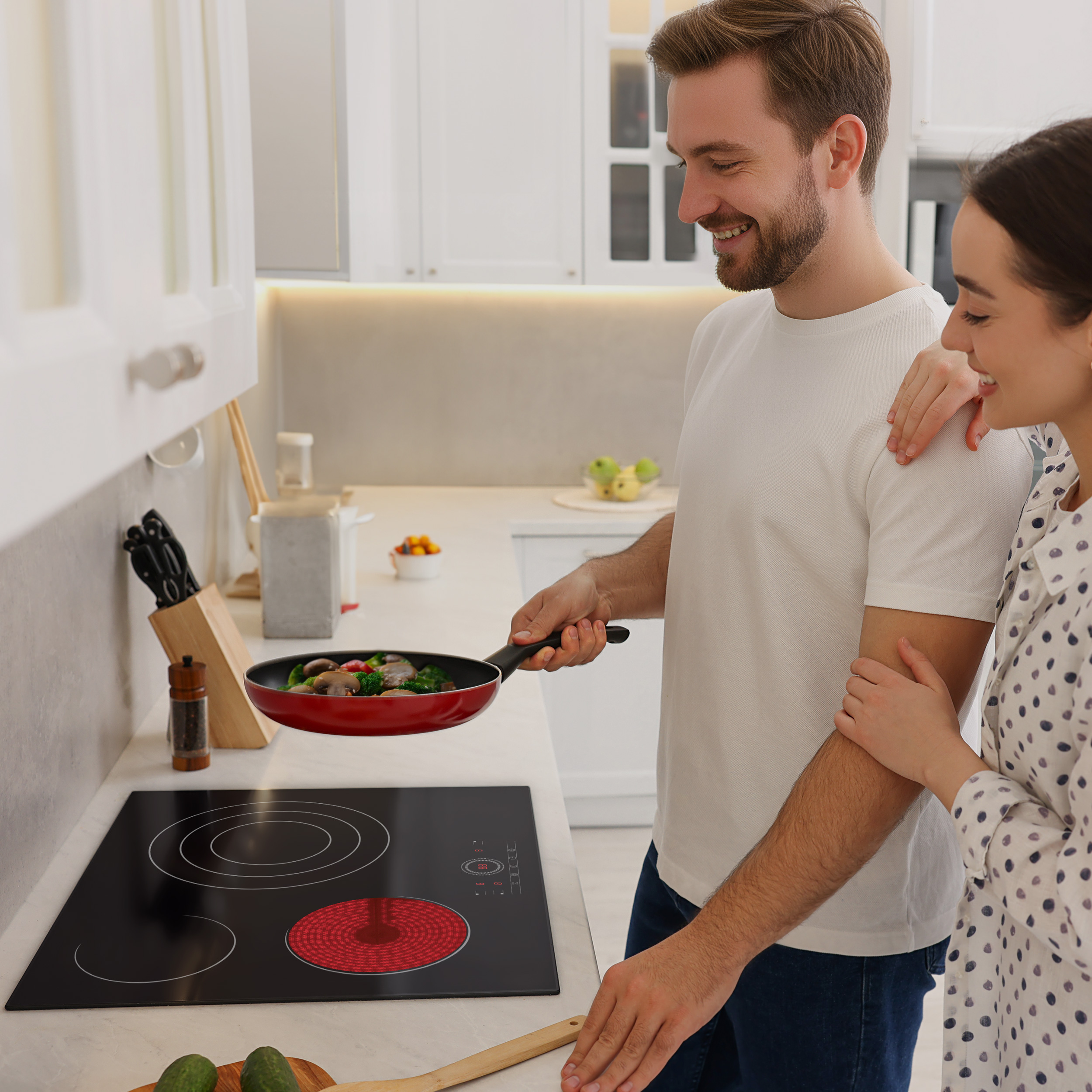 Un homme cuisine avec une femme. Il tient une poêle avec de la nourriture. Ils sont dans une cuisine.