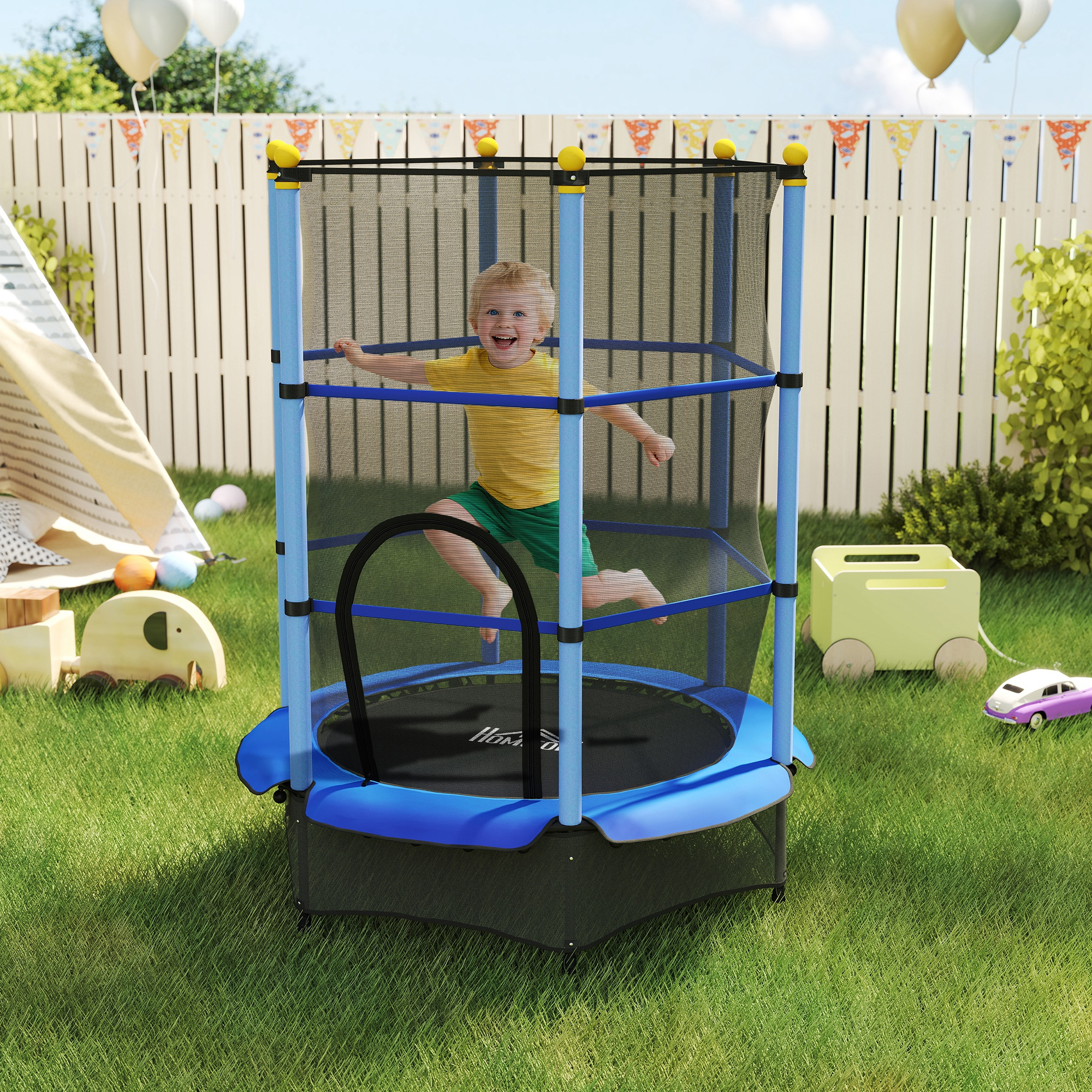 Un niño salta en una cama elástica azul en un jardín. Globos y una valla blanca al fondo.