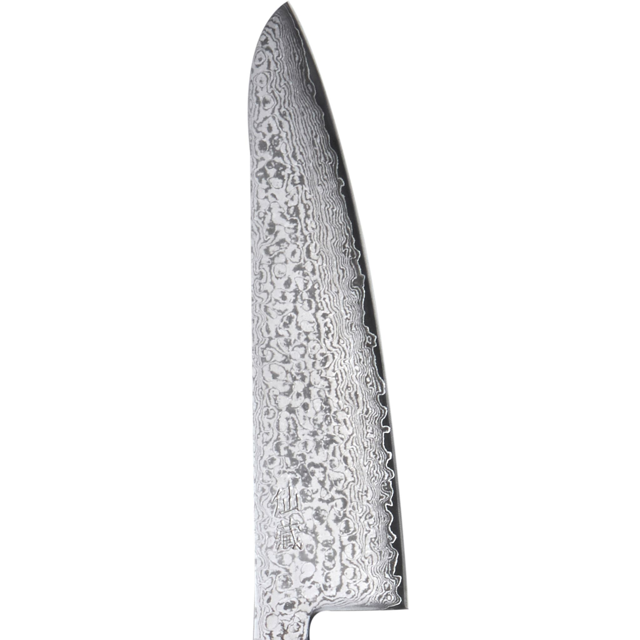 Nahaufnahme einer Messerklinge mit gemusterter Oberfläche. Die Klinge ist scharf und hat eine wellenartige Kante. Weißer Hintergrund.