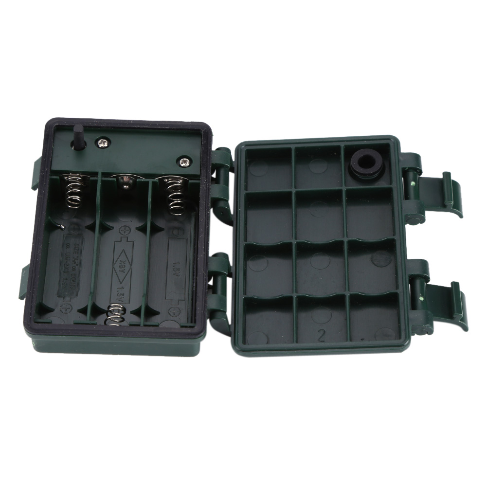 Offener grüner Batteriefach. Die linke Seite enthält Batterien. Die rechte Seite ist in Quadrate unterteilt. Scharniere sind sichtbar.
