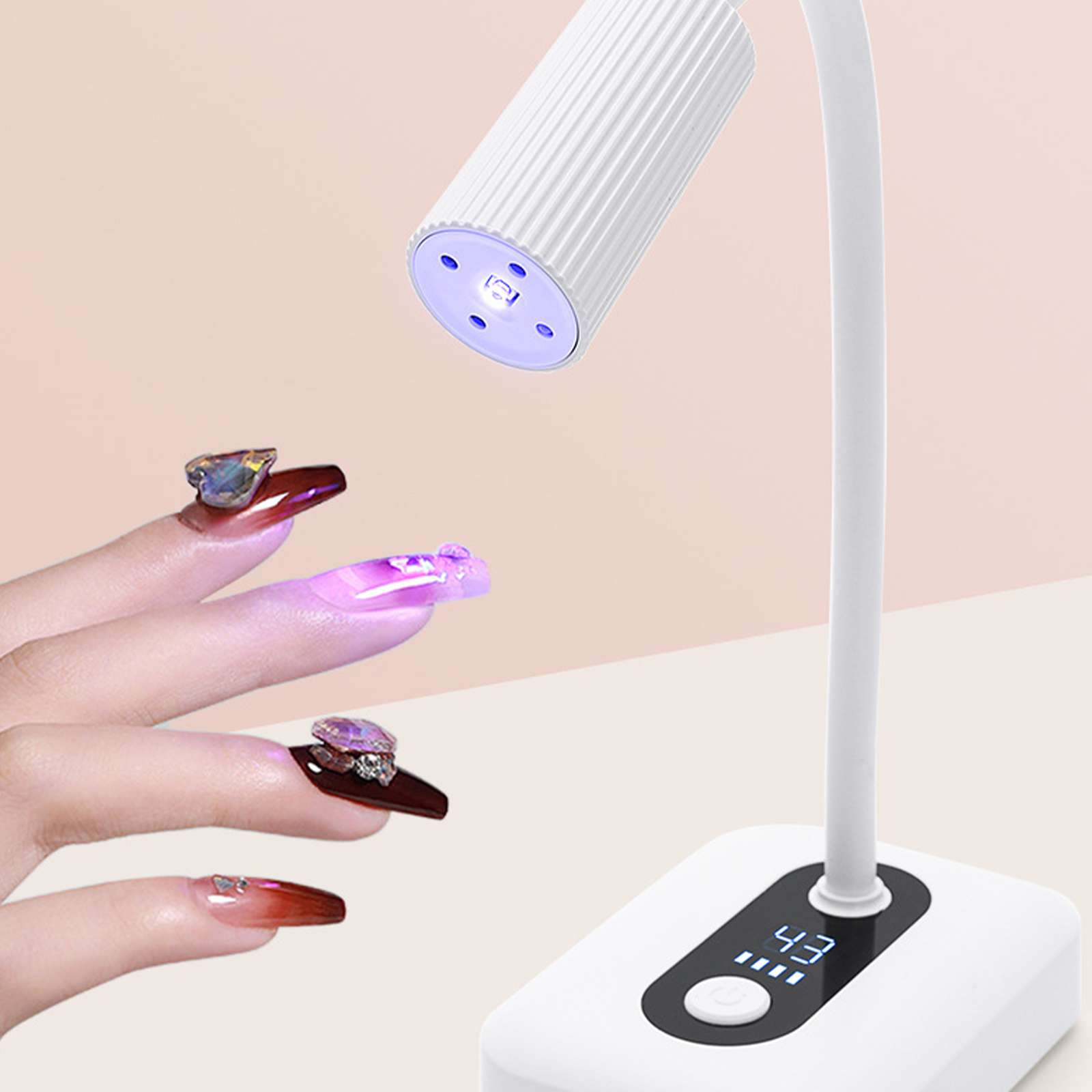 Eine Nagellampe scheint auf manikürte Nägel. Die Nägel haben Edelsteine und sind in verschiedenen Farben gehalten. Die Lampe hat einen Bildschirm.