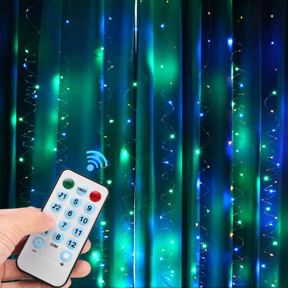 Hand hält Fernbedienung für Lichterketten. Grüne und blaue Lichter an einem Vorhang. Die Fernbedienung hat Knöpfe.