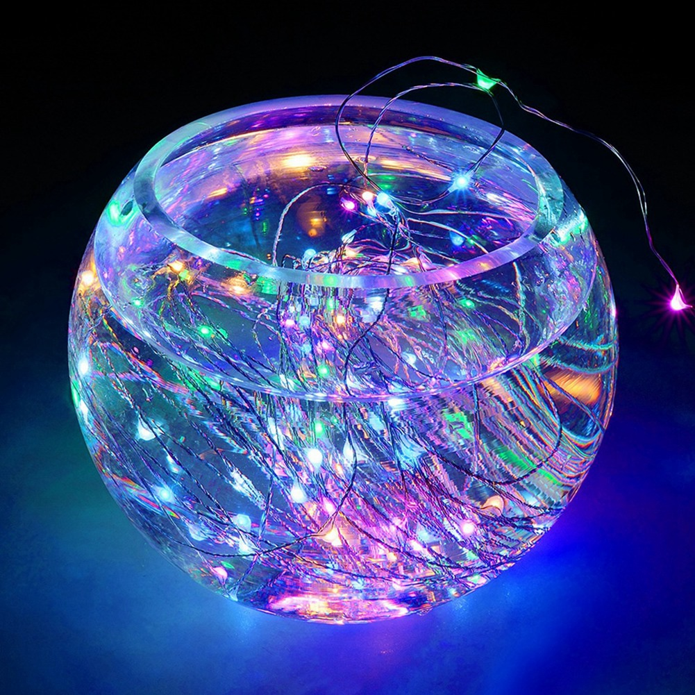 Eine klare Glasschale mit Wasser und bunten Lichterketten. Die Lichter erzeugen eine lebendige und beleuchtete Anzeige vor einem dunklen Hintergrund.