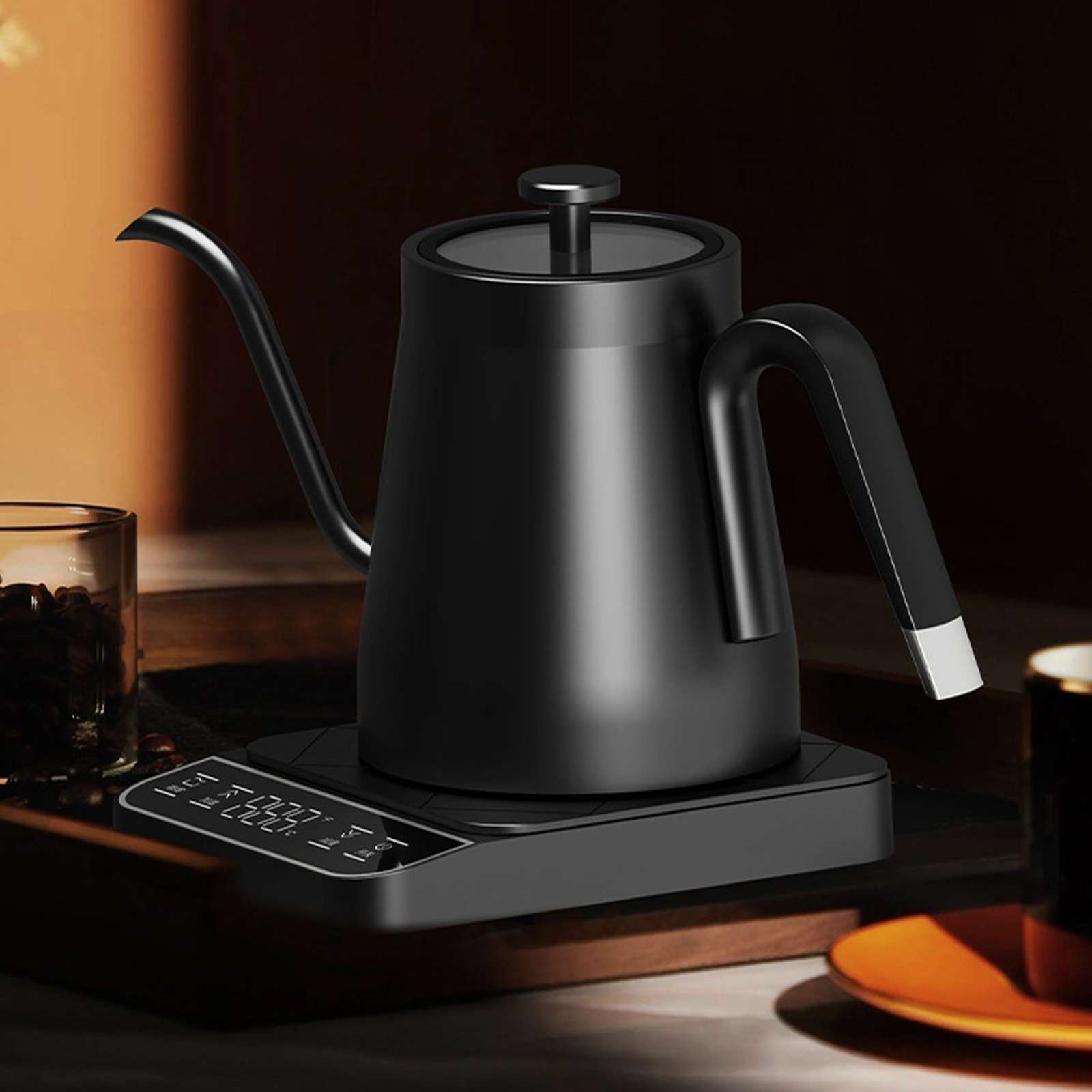 Ein schwarzer Schwanenhalskessel auf schwarzer Basis. Links ein Glas Kaffeebohnen. Rechts eine Tasse und Untertasse.