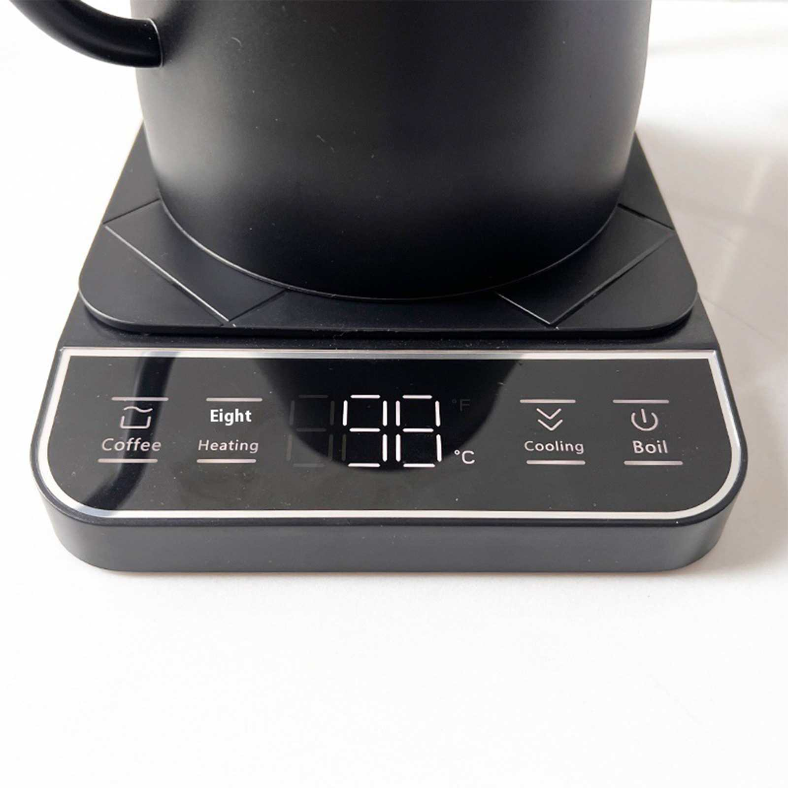 Ein schwarzer Wasserkocher auf einem schwarzen Sockel mit digitaler Temperaturanzeige. Knöpfe für Kaffee, Erhitzen, Abkühlen und Kochen.