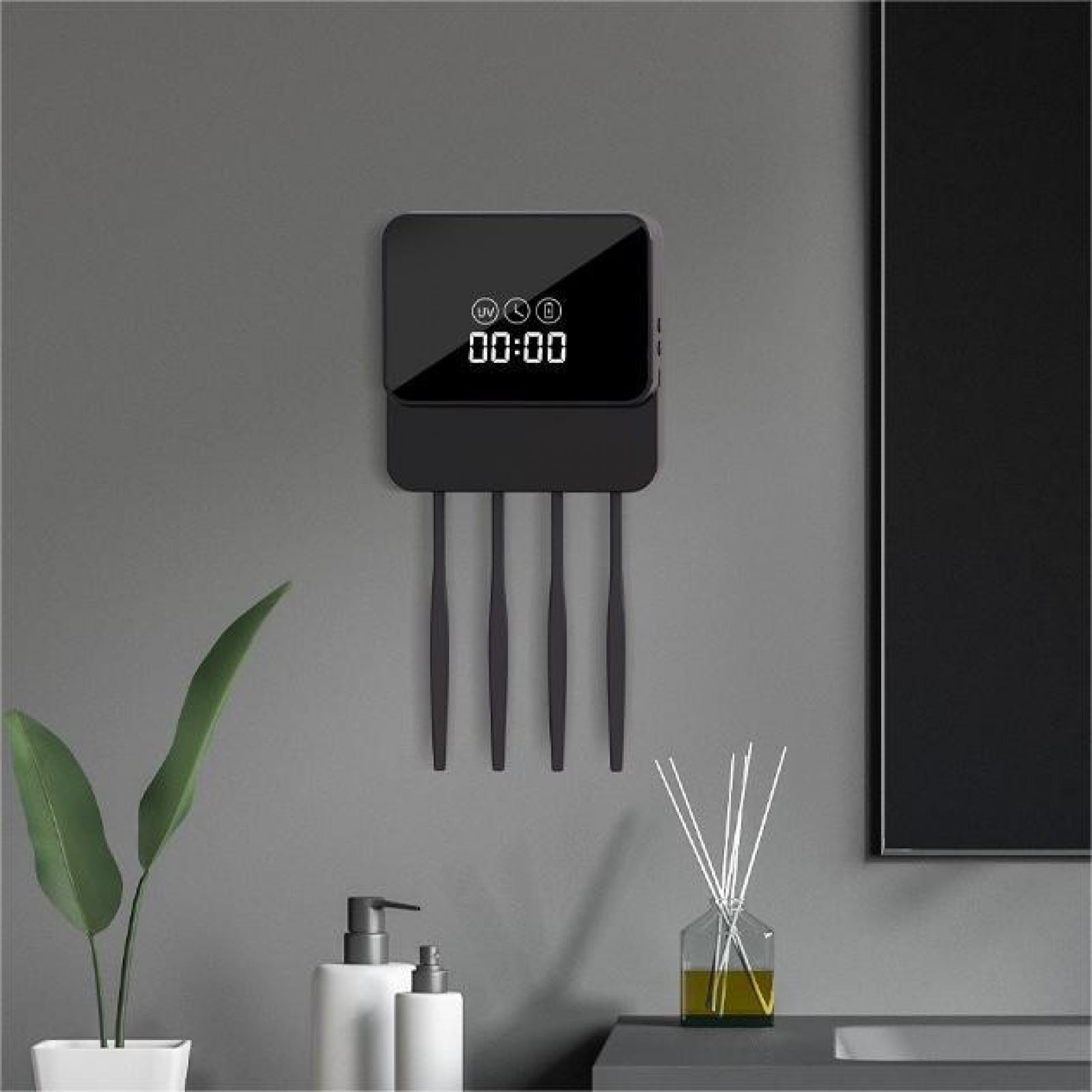 Schwarzes Gerät mit Digitaluhr, Zahnbürstenhaltern und Badezimmerzubehör an einer grauen Wand.