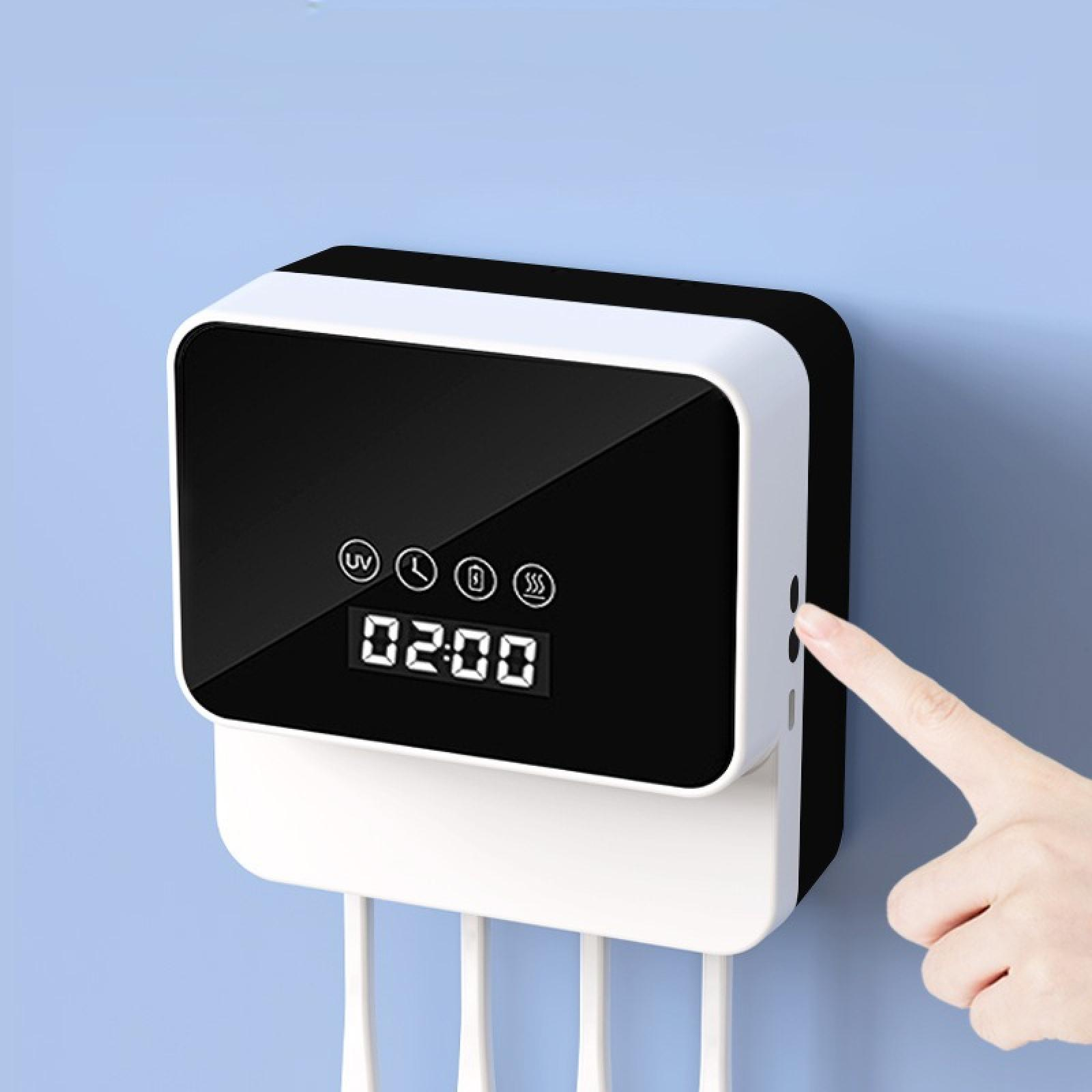 Ein weißer und schwarzer Zahnbürsten-Sterilisator mit Digitaluhr und drei Zahnbürstenhaltern. Eine Hand berührt das Gerät.