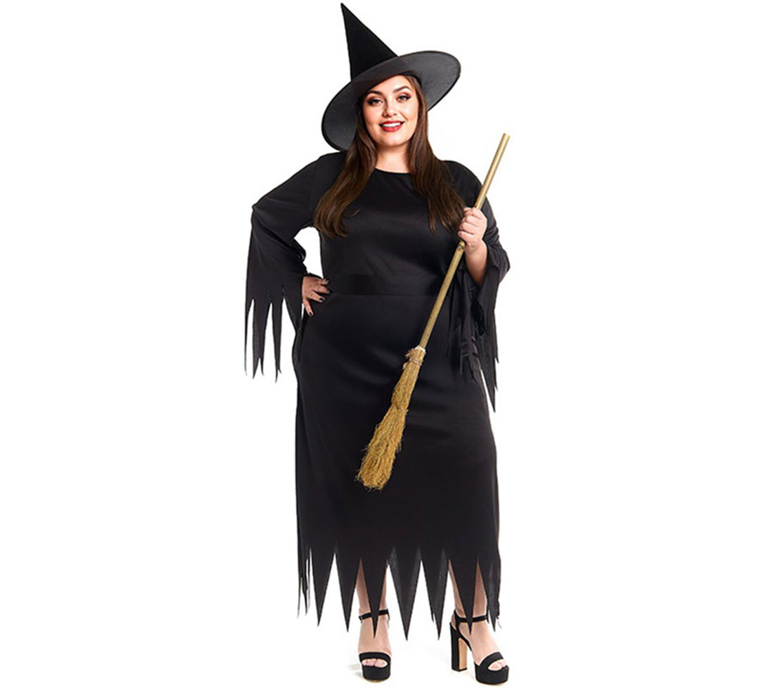 Una mujer con disfraz de bruja, vestido y sombrero negros, sosteniendo una escoba. Sonríe y está de pie sobre fondo blanco.