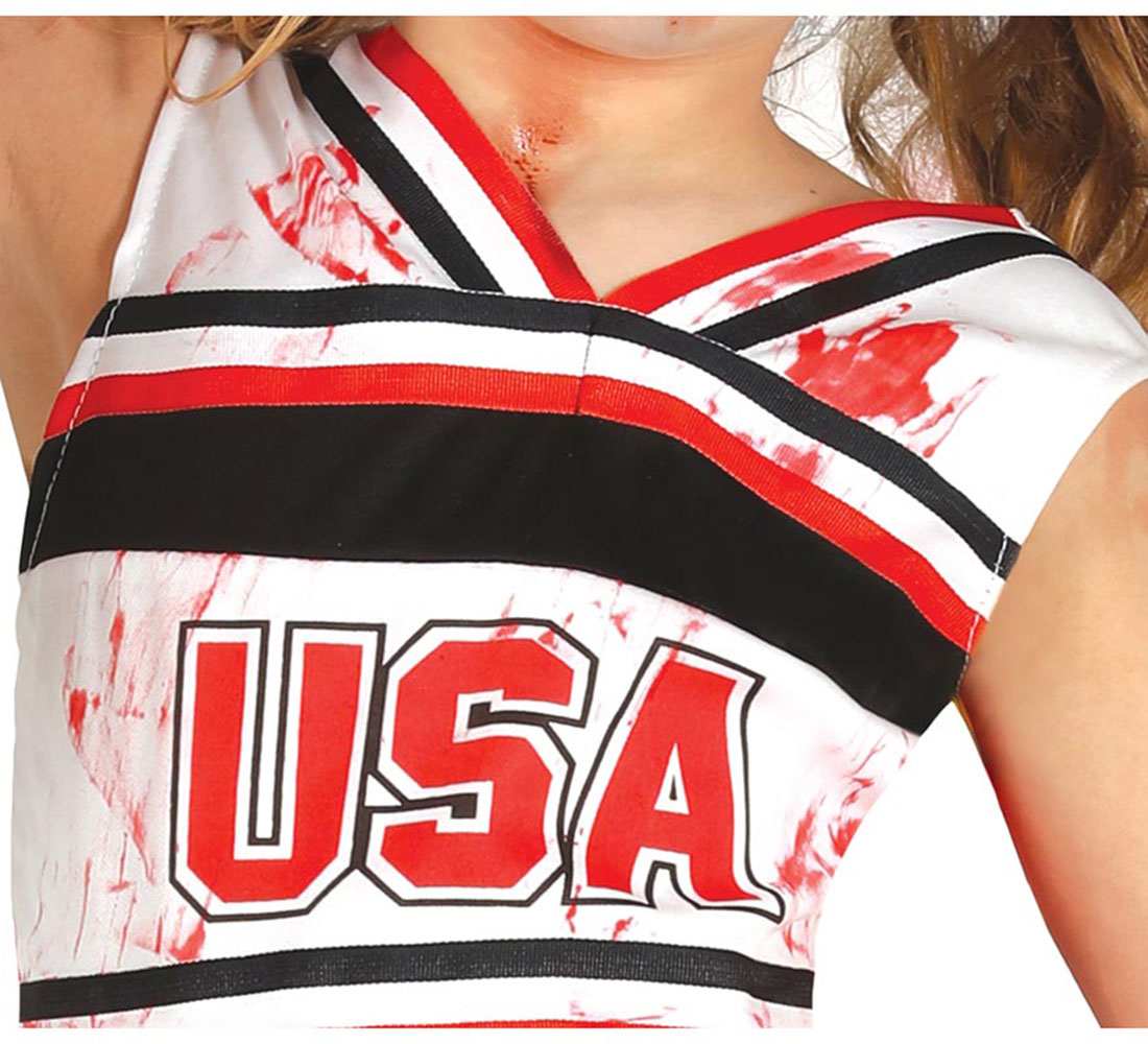 Una persona vestida con un uniforme de animadora blanco con 'USA' en rojo. El uniforme tiene rayas rojas, negras y blancas, salpicadas de rojo.