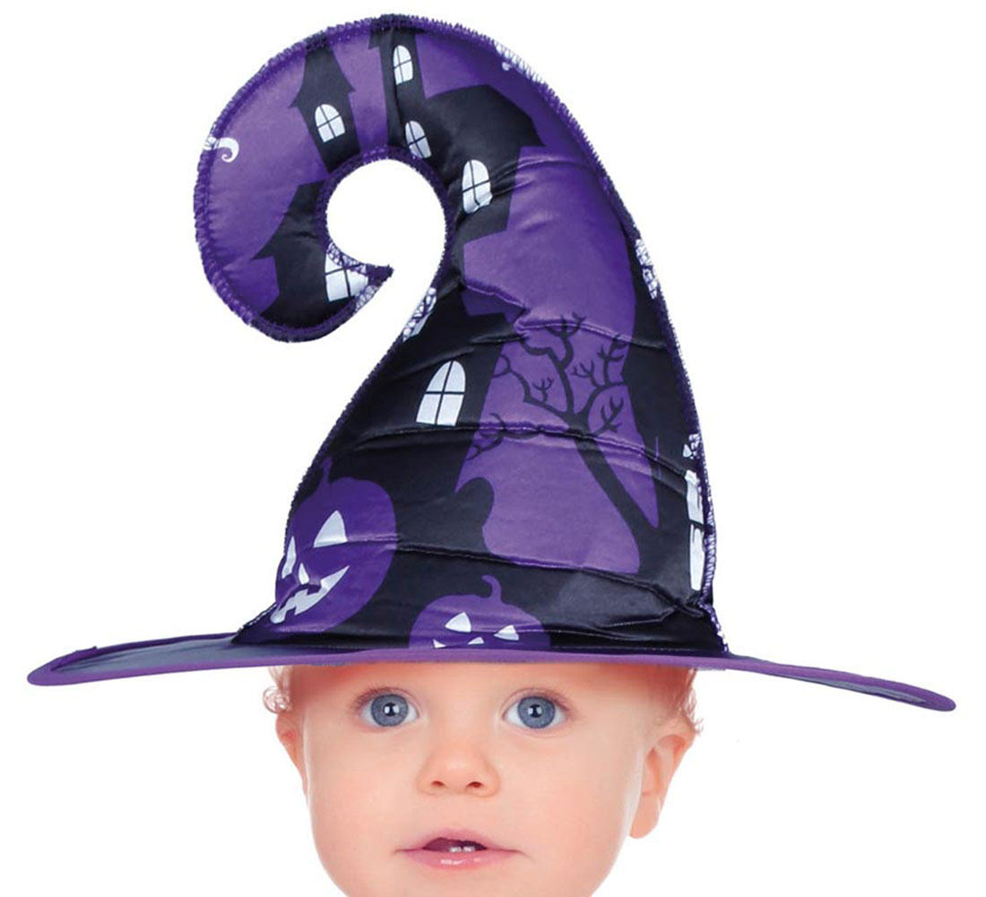 Un bebé con un sombrero de bruja morado decorado con casas embrujadas y calabazas negras. El bebé tiene ojos azules y piel clara.