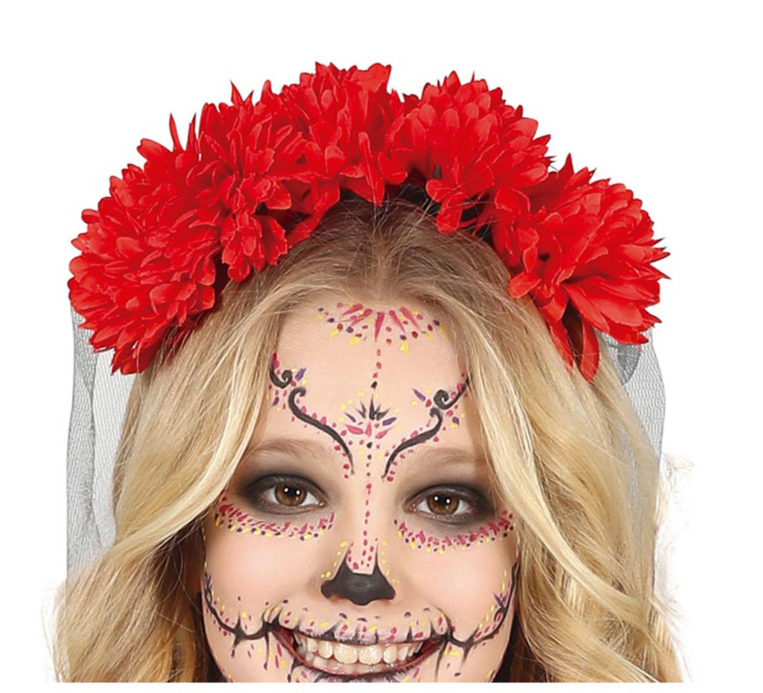 Una mujer con maquillaje del Día de Muertos y una corona de flores rojas sonríe. Su rostro está pintado con patrones detallados.