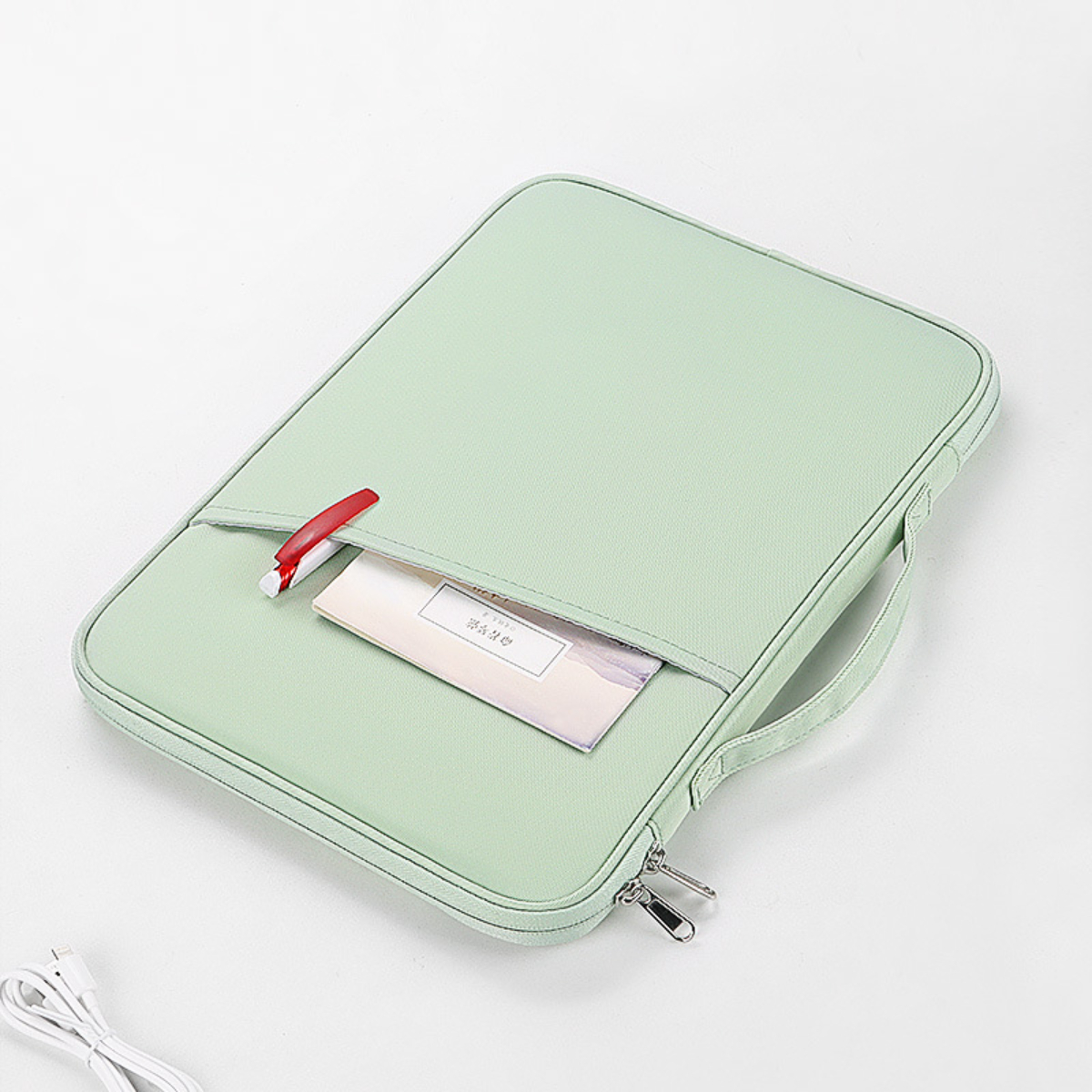 Eine hellgrüne Laptoptasche mit einem Stift und einer Karte in der Tasche. Ein Ladekabel befindet sich unten links.