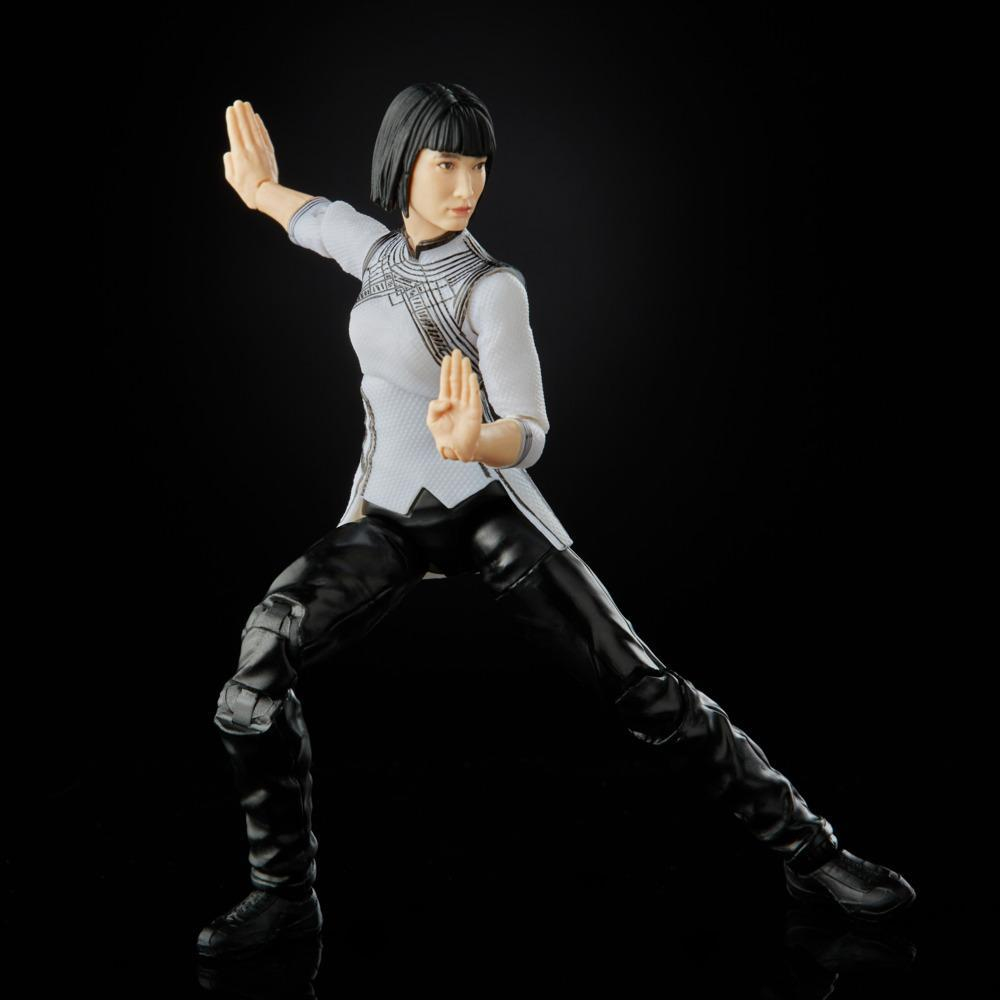 Eine weibliche Actionfigur in einer Kampfsportpose. Sie trägt ein weißes Oberteil und eine schwarze Hose. Der Hintergrund ist einfach schwarz.