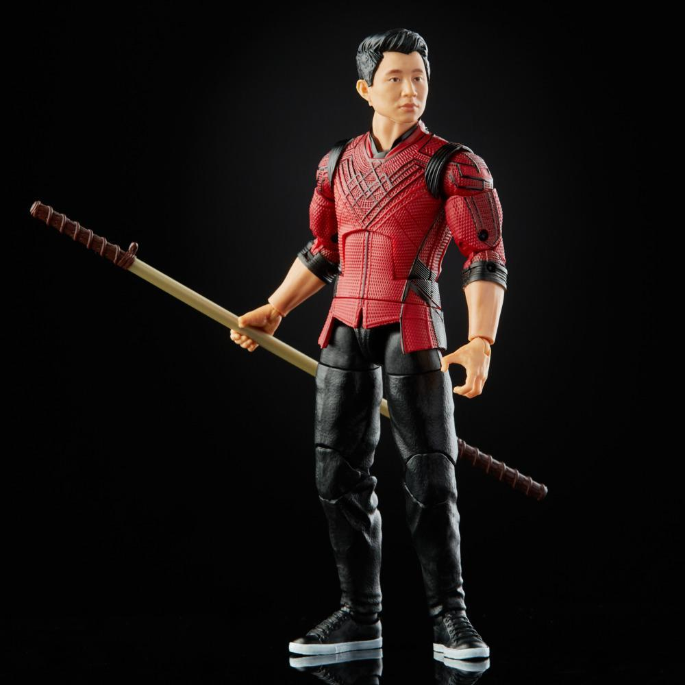 Action figure di un uomo in abito rosso e nero, con un bastone. Lo sfondo è nero, con il riflesso della figura.