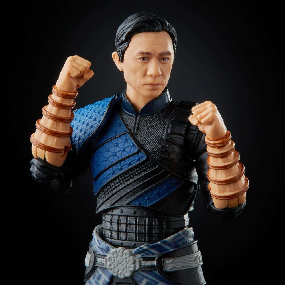 Action figure di un uomo in abito blu e nero, pugni chiusi. Bracciali marroni adornano gli avambracci. Lo sfondo è nero.