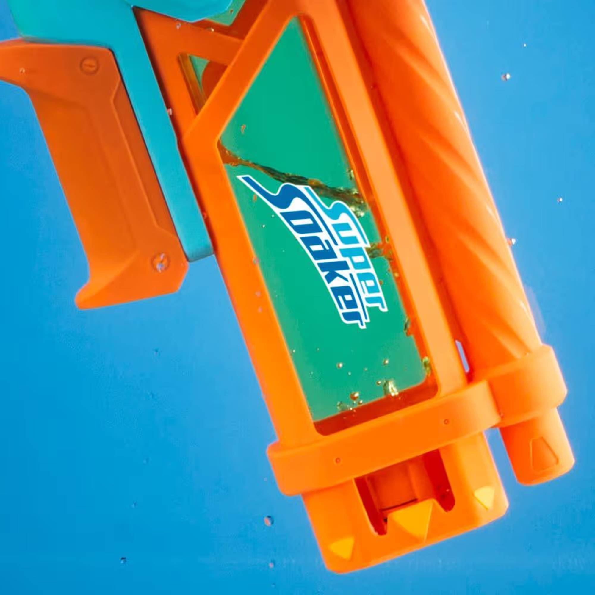 Orange und teal Super Soaker Wasserpistole vor blauem Hintergrund. Grünes Etikett mit Logo. Wassertropfen sichtbar.
