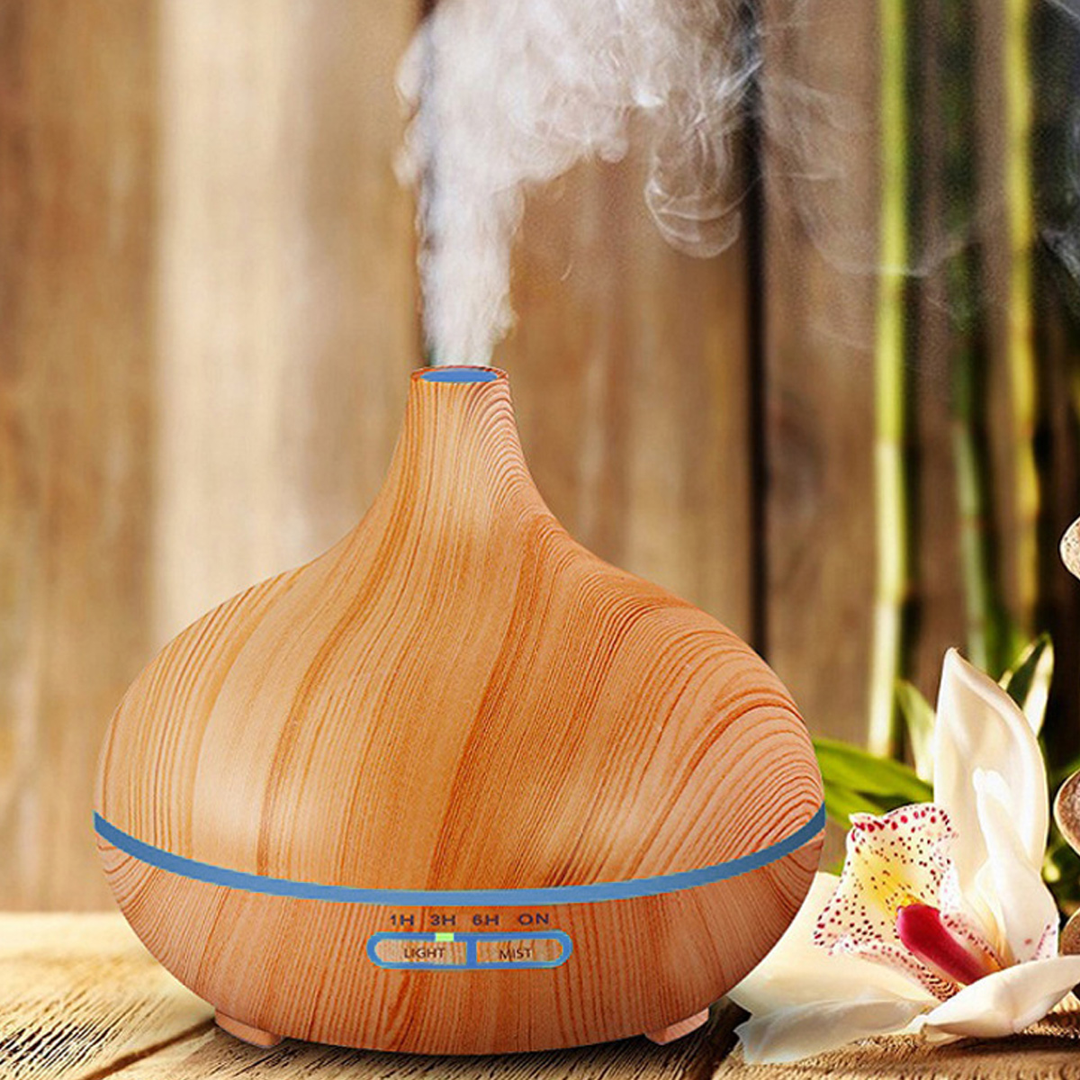 Ein Diffusor für ätherische Öle mit Holzmaserung steht auf einem Holztisch. Weißer Dampf steigt auf. Eine weiße Orchidee und Bambus sind im Hintergrund.