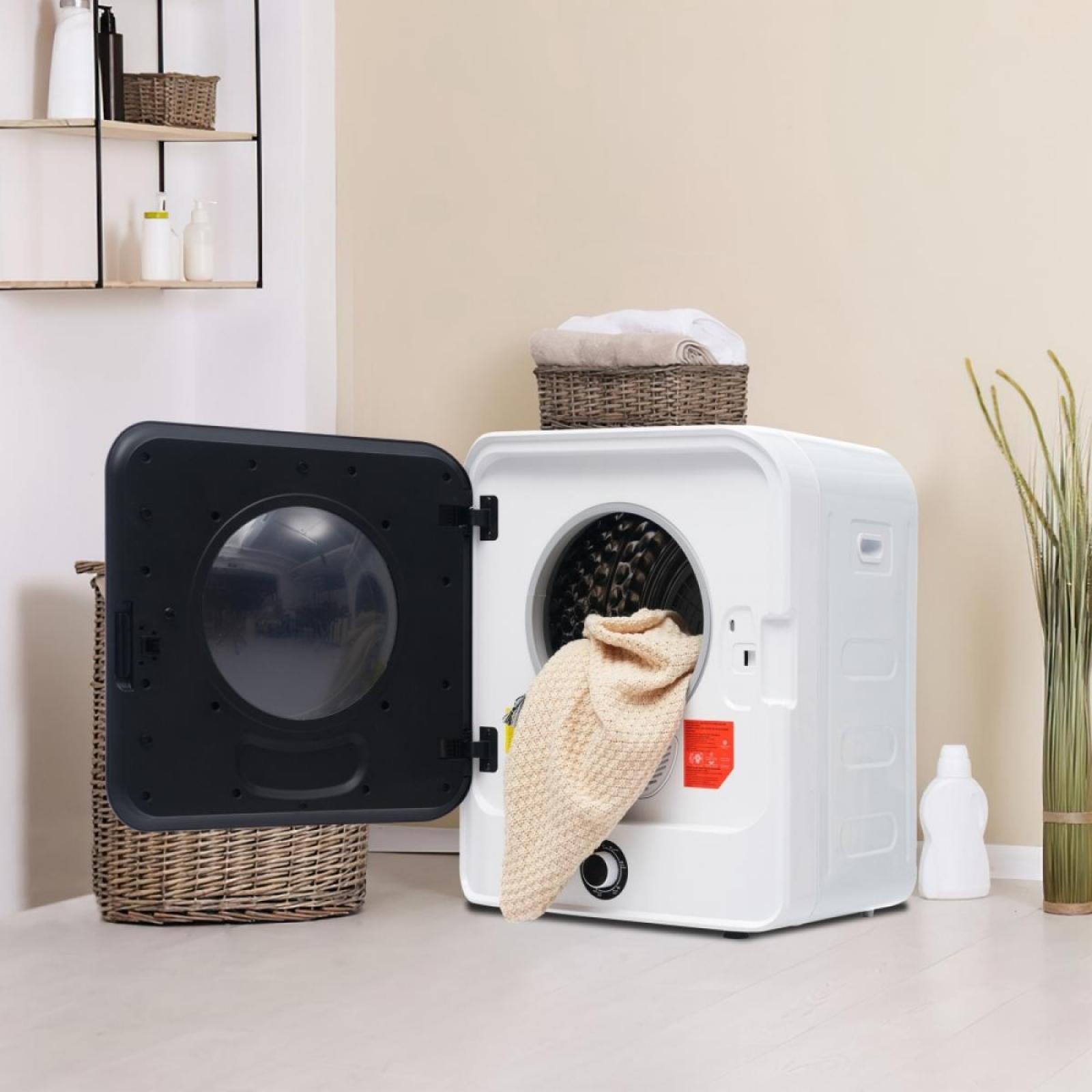Ein weißer Trockner mit offener Tür, in dem eine beige Decke zu sehen ist. Obenauf befindet sich ein Korb mit Handtüchern.