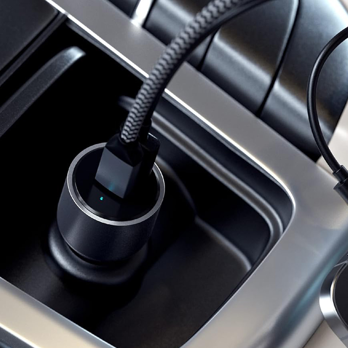 Un caricabatterie per auto è collegato a una presa di corrente dell'auto. Il caricabatterie è nero e argento, con un cavo intrecciato.