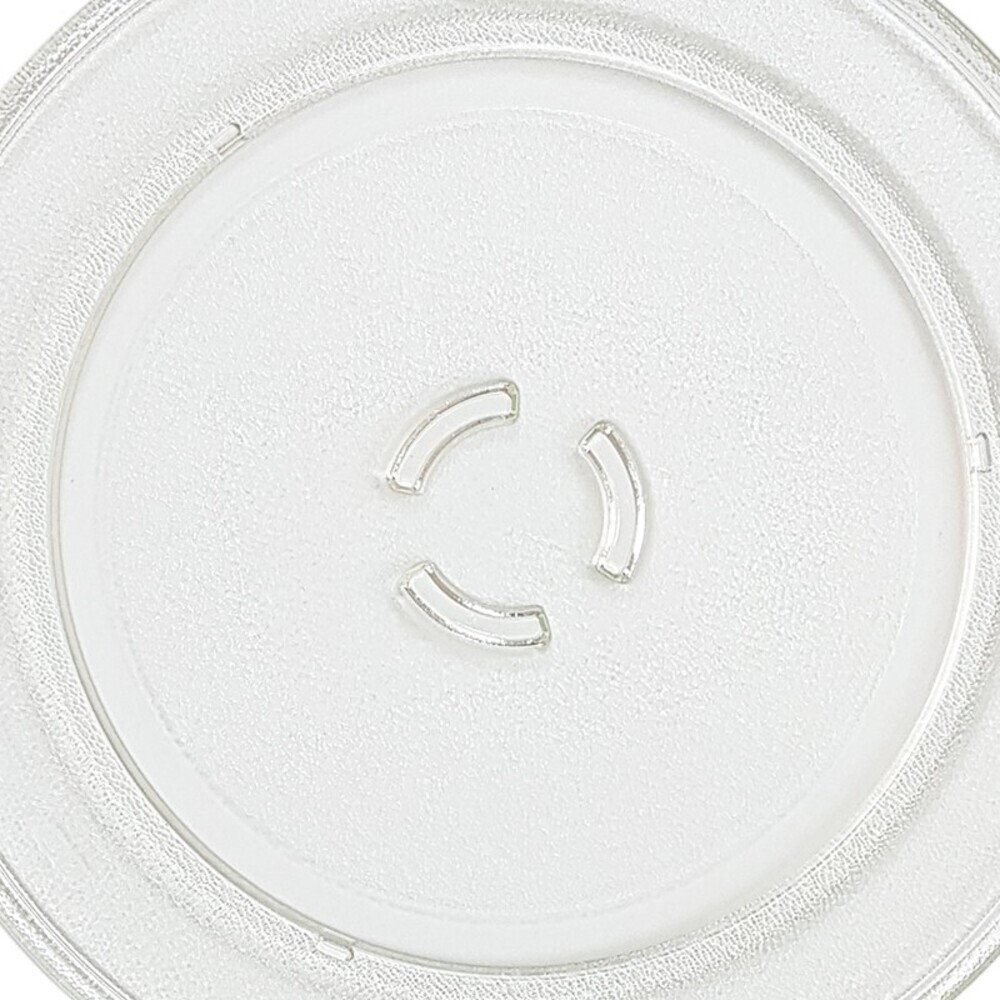 Una placa de microondas de vidrio transparente y circular. Tiene tres soportes curvos y elevados en el centro y un borde texturizado.