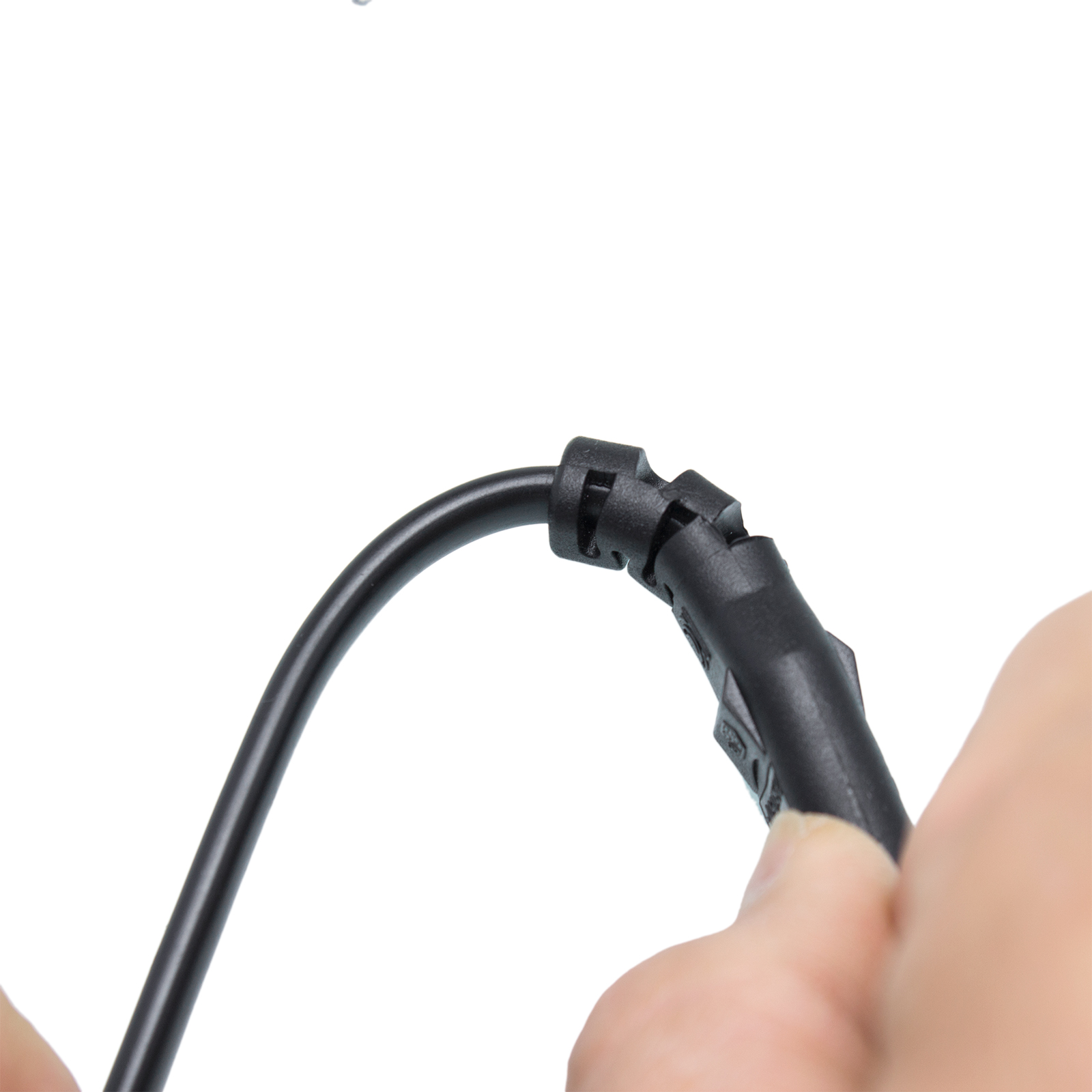 Ein schwarzes Kabel und ein Stecker werden von einer Hand vor weißem Hintergrund gehalten. Der Stecker wird gehalten.