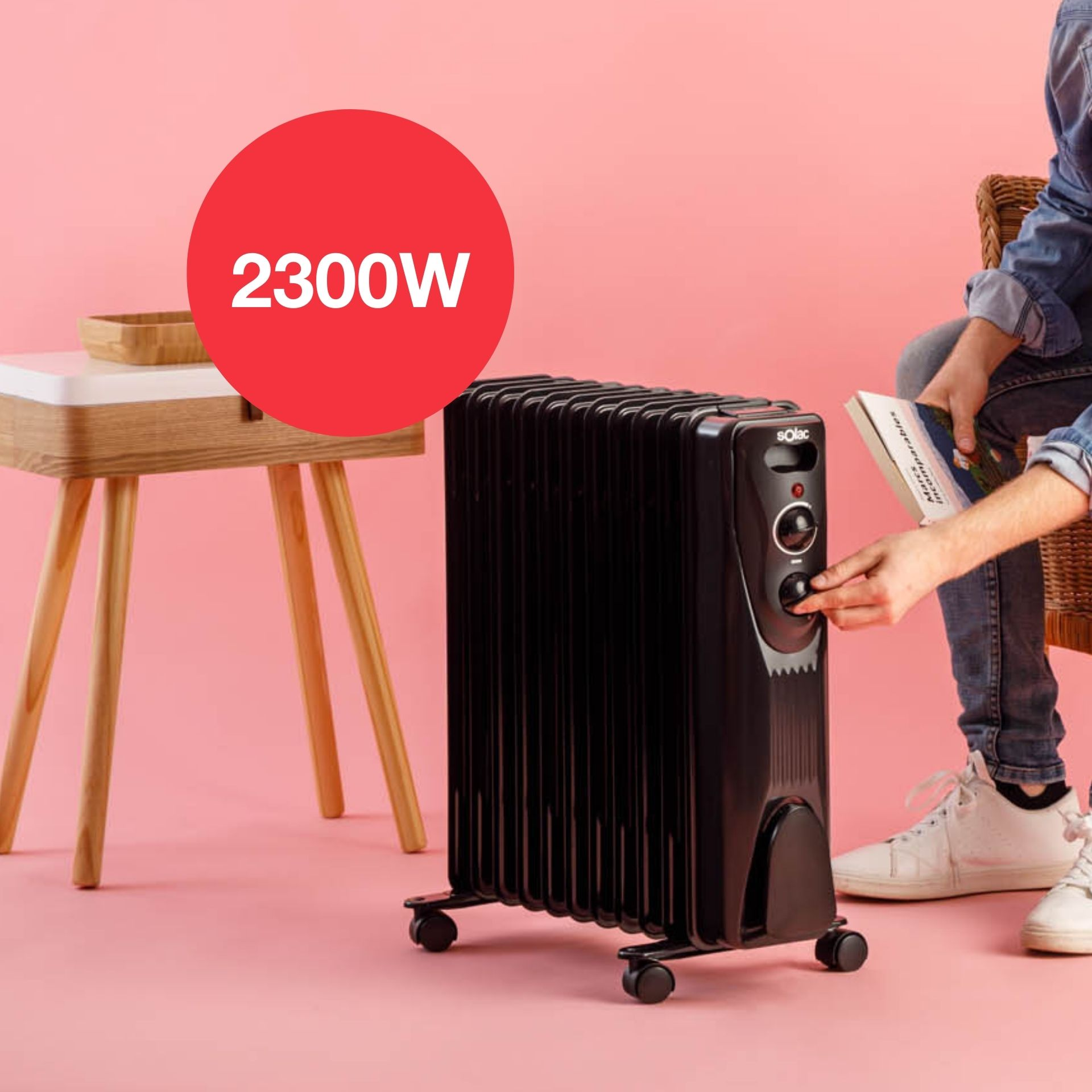 Ein schwarzer Ölradiator, an dem eine Person die Regler einstellt. Ein roter Kreis zeigt 2300W. Rosa Hintergrund.