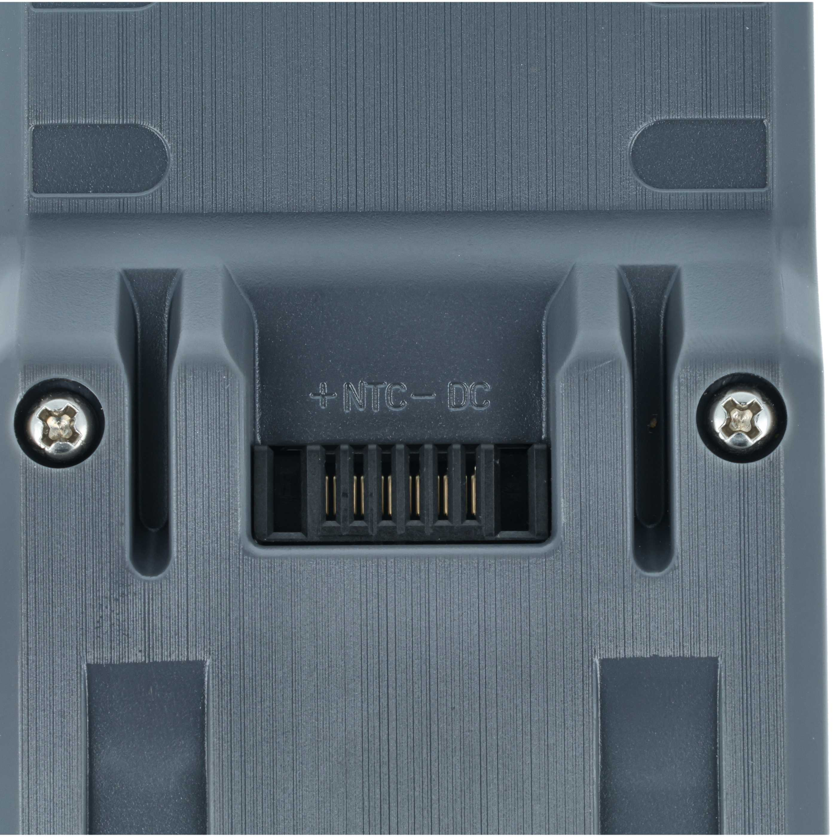 Nahaufnahme einer grauen Kunststoffkomponente. Sie hat einen Stecker mit Pins und zwei Schrauben. Der Text '+NTC-DC' ist sichtbar.