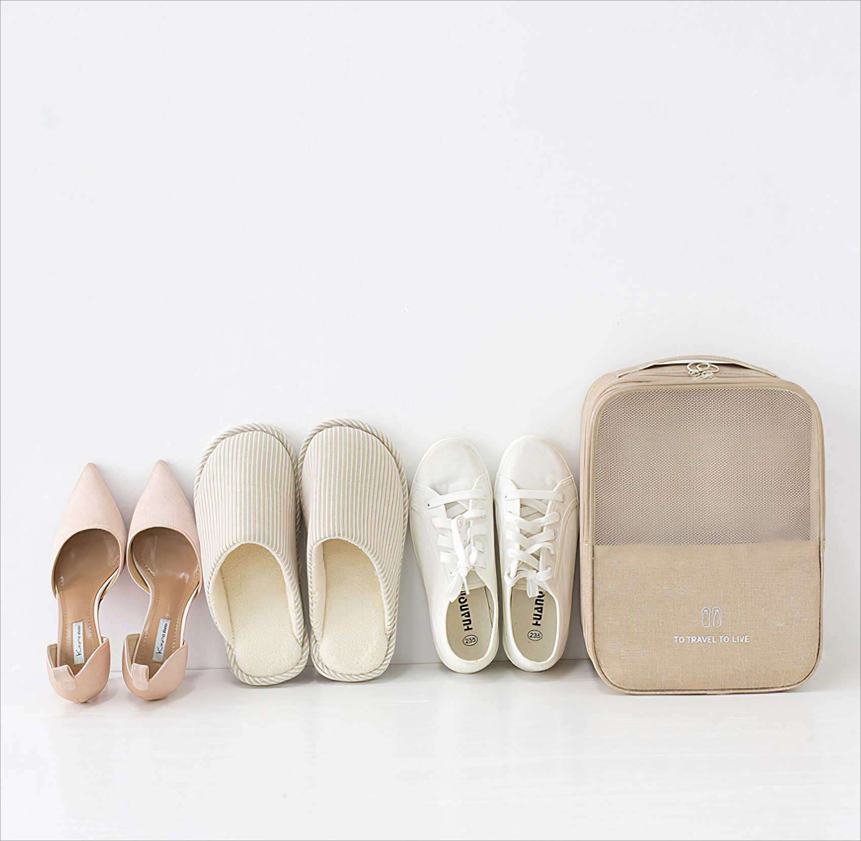 Schuhe, Hausschuhe und eine Reisetasche sind auf einer weißen Oberfläche angeordnet. Die Schuhe sind Absätze und Turnschuhe.