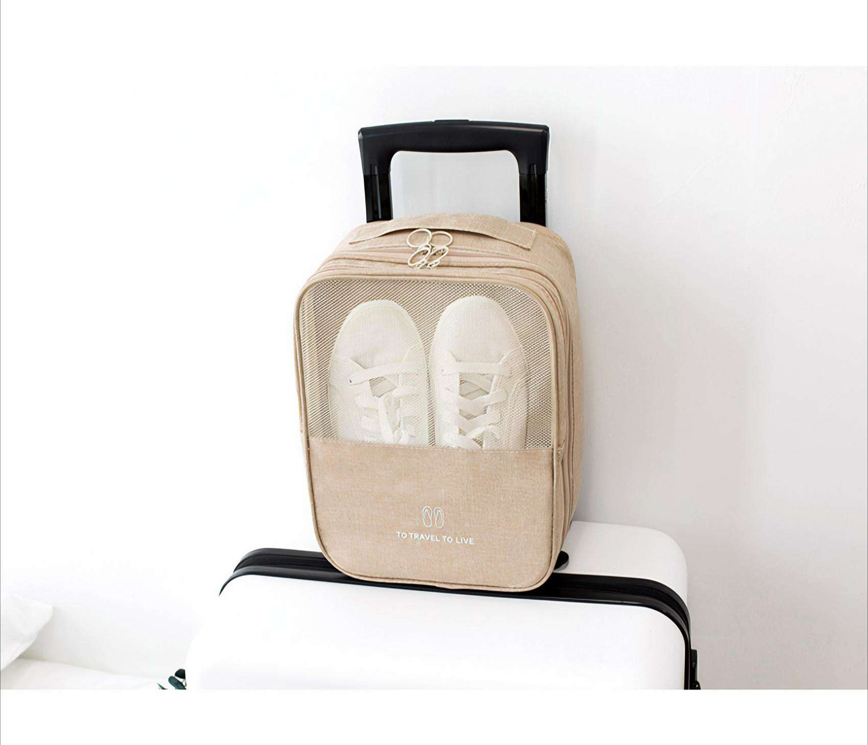 Beige Schuhtasche mit weißen Schuhen darin, platziert auf einem weißen Koffer mit schwarzem Griff. Der Hintergrund ist weiß.