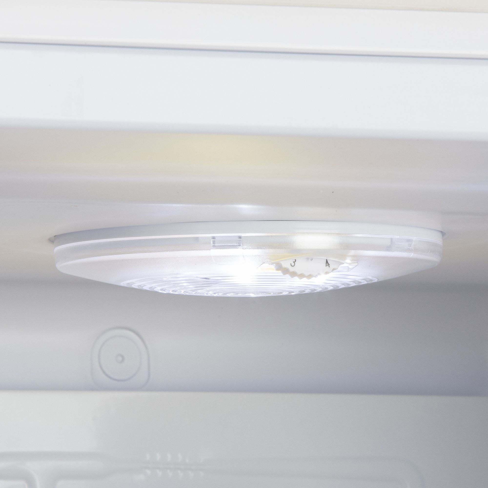 All'interno di un frigorifero, è visibile un apparecchio di illuminazione bianco e rotondo con un quadrante. È posizionato sul soffitto del frigorifero.
