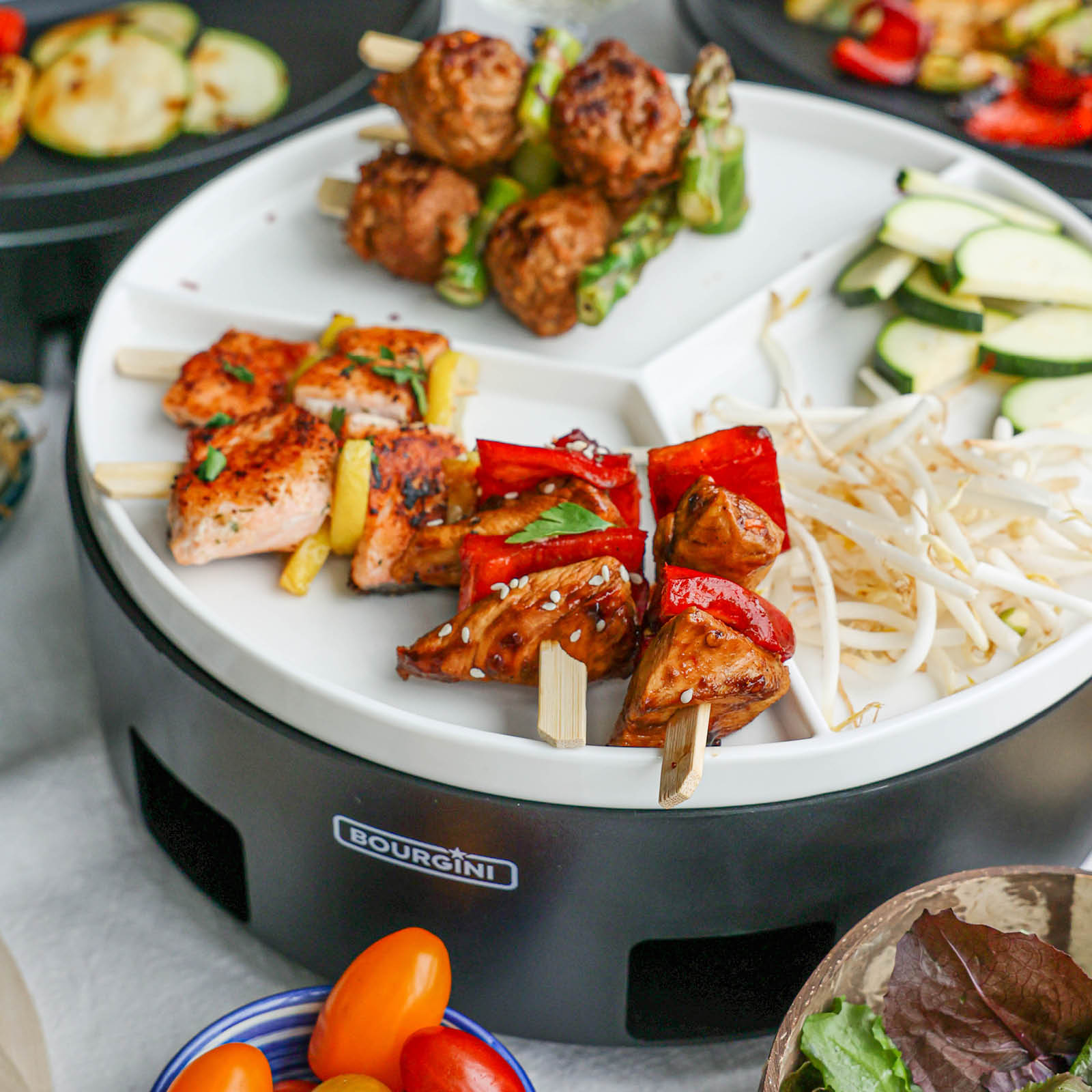 Skewers with meat, vegetables and bean sprouts on a white plate, small tomatoes and salad in bowls, zucchini slices.