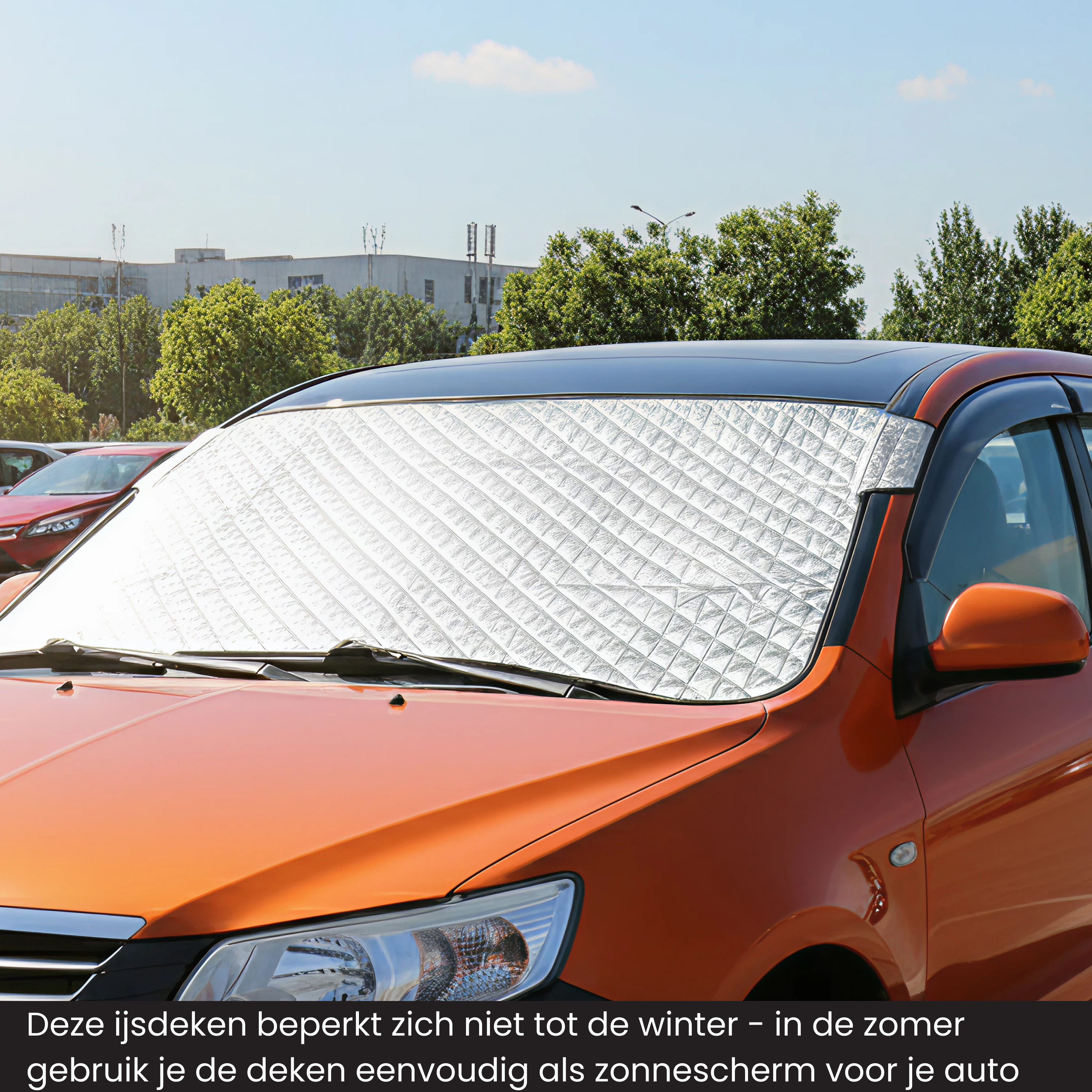 An orange car has a reflective windshield cover. Trees and buildings are in the background under a blue sky.