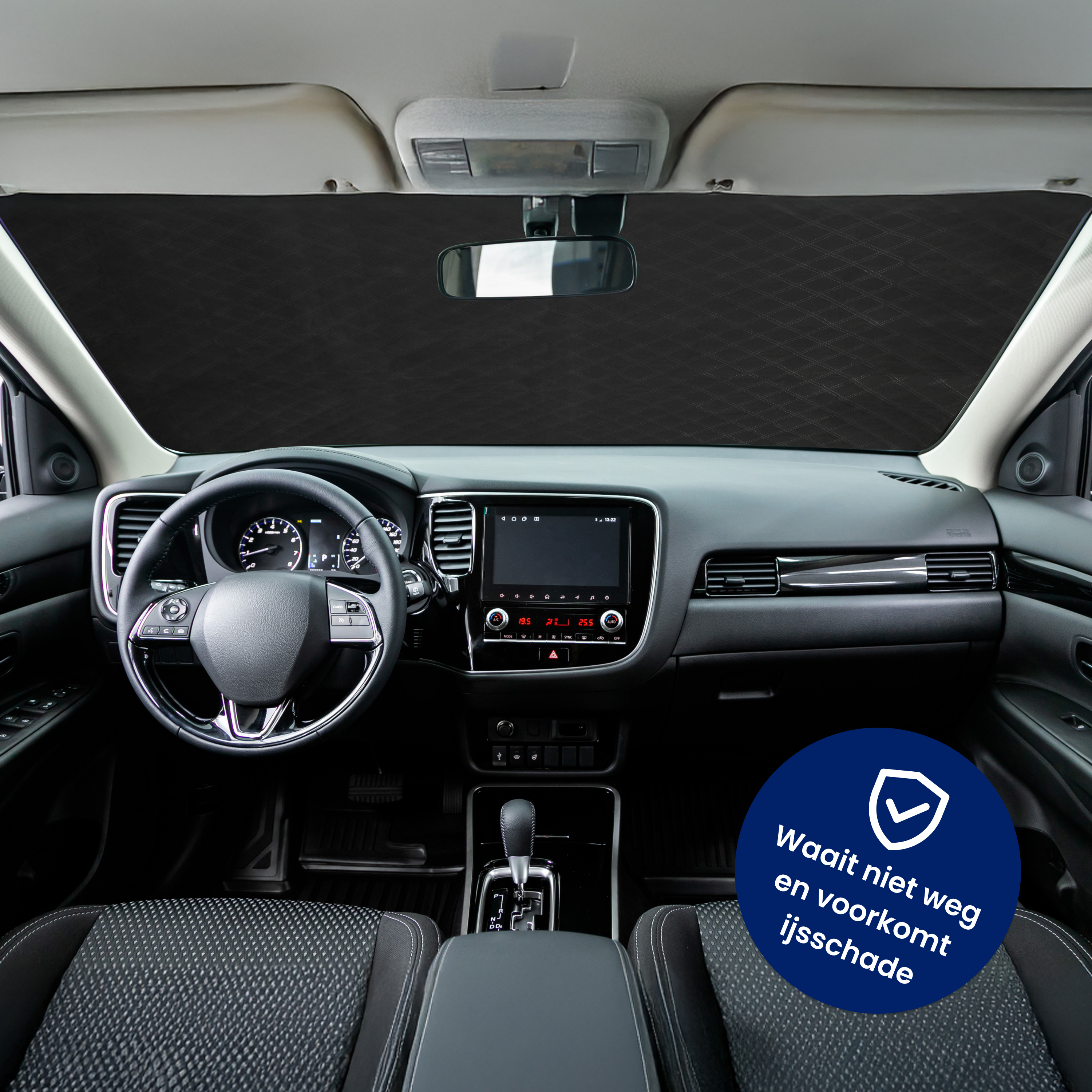 Interior car view with a black dashboard. A windshield cover is in place. A badge says: Waait niet weg en voorkomt ijsschade.