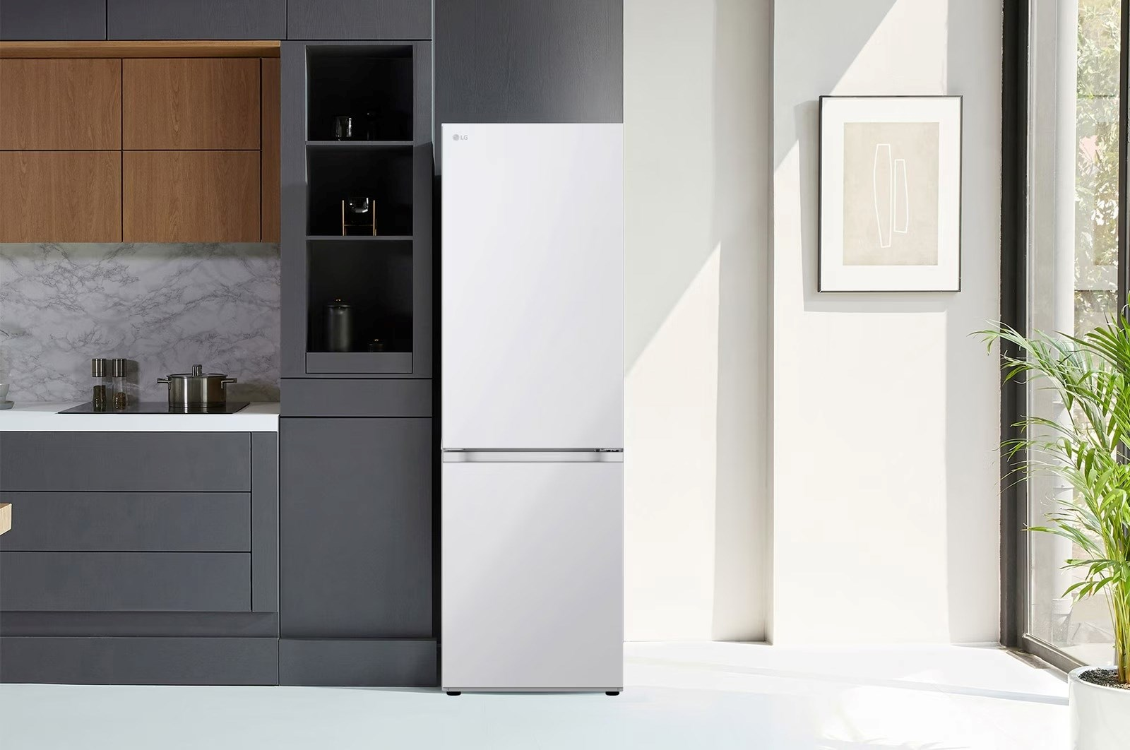 Biała lodówka LG w nowoczesnej kuchni. Szare szafki i marmurowa ściana z lewej. Roślina po prawej.