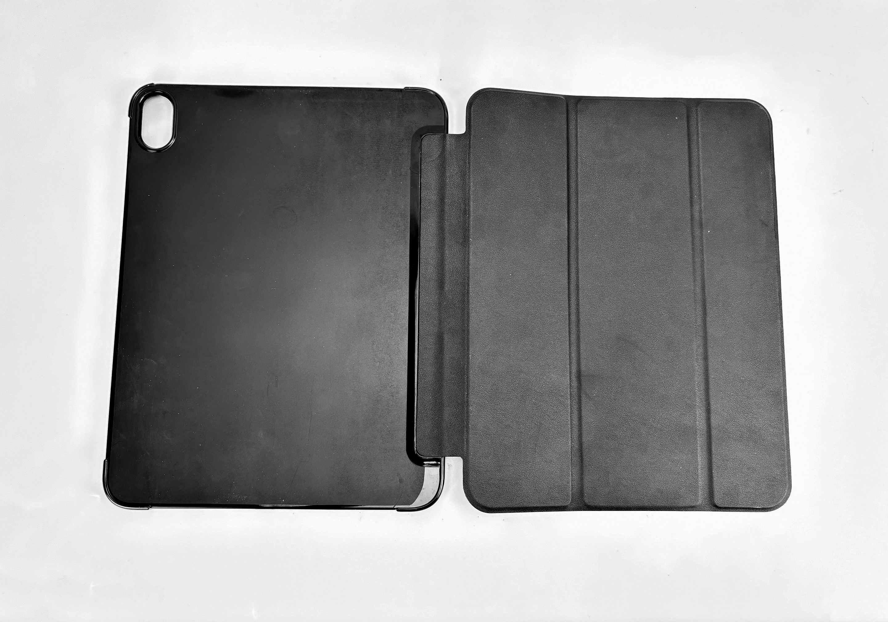 Una custodia per tablet nera, aperta, su una superficie bianca. La custodia aperta rivela un interno scuro e strutturato.