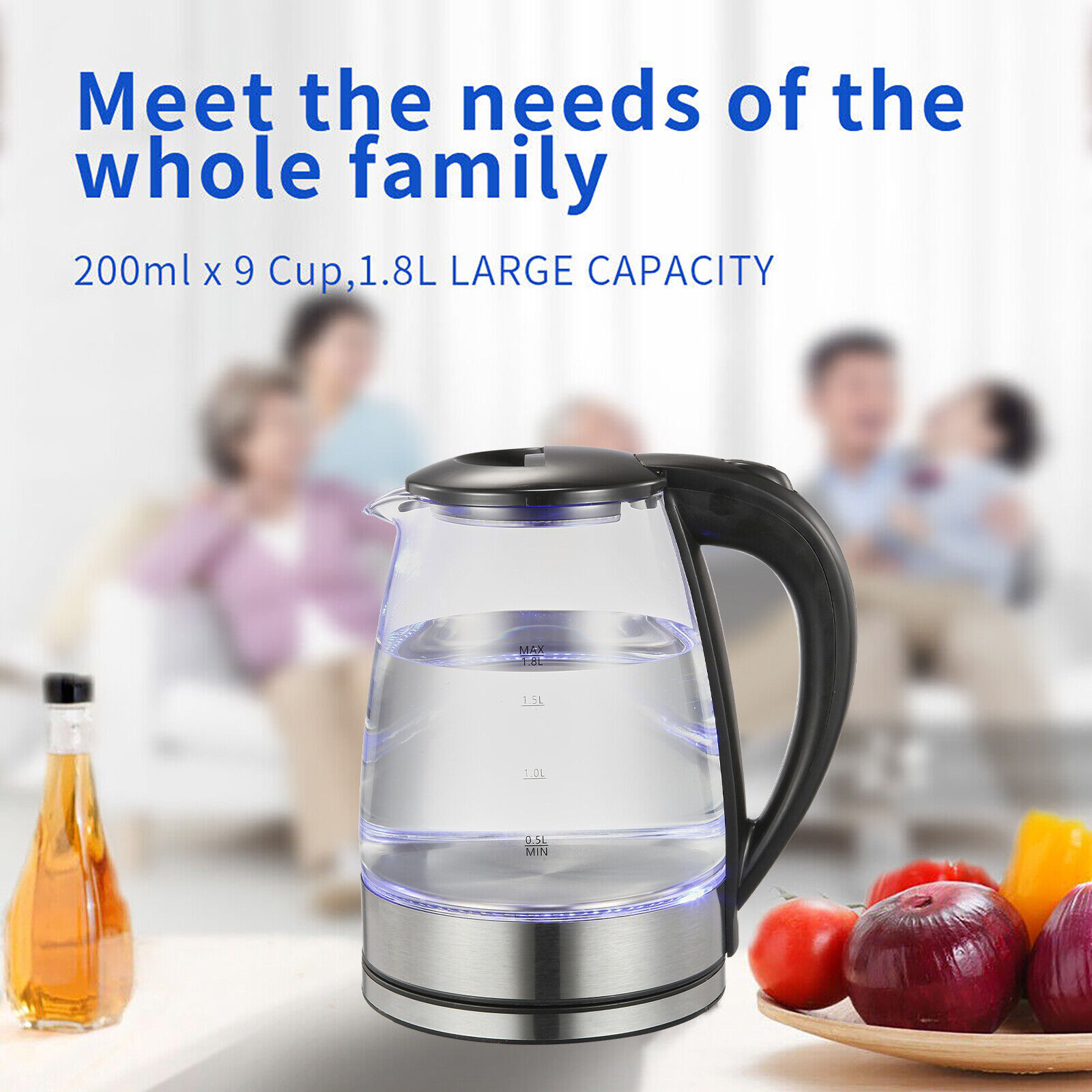 Ein gläserner Wasserkocher mit Wasser, daneben Obst und Gemüse. Familie im verschwommenen Hintergrund.