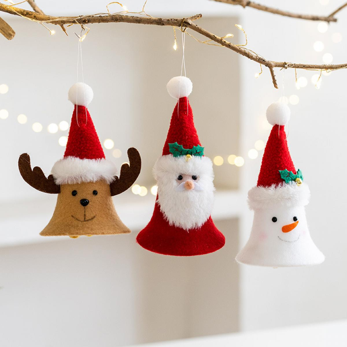 Drei Weihnachtsschmuckstücke: ein Rentier, der Weihnachtsmann und ein Schneemann. Sie hängen an einem Ast mit Lichtern im Hintergrund.