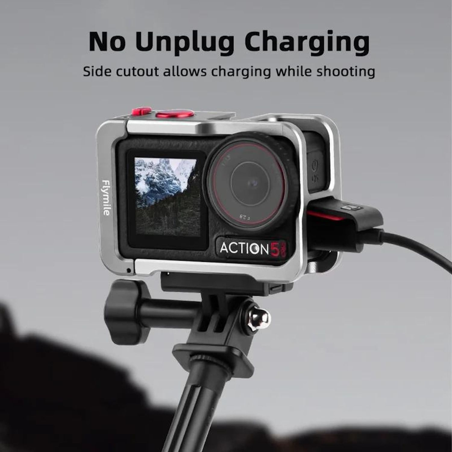 Fotocamera argentata in custodia, montata su un treppiede. Lo schermo mostra una scena di montagna. Testo: No Unplug Charging.