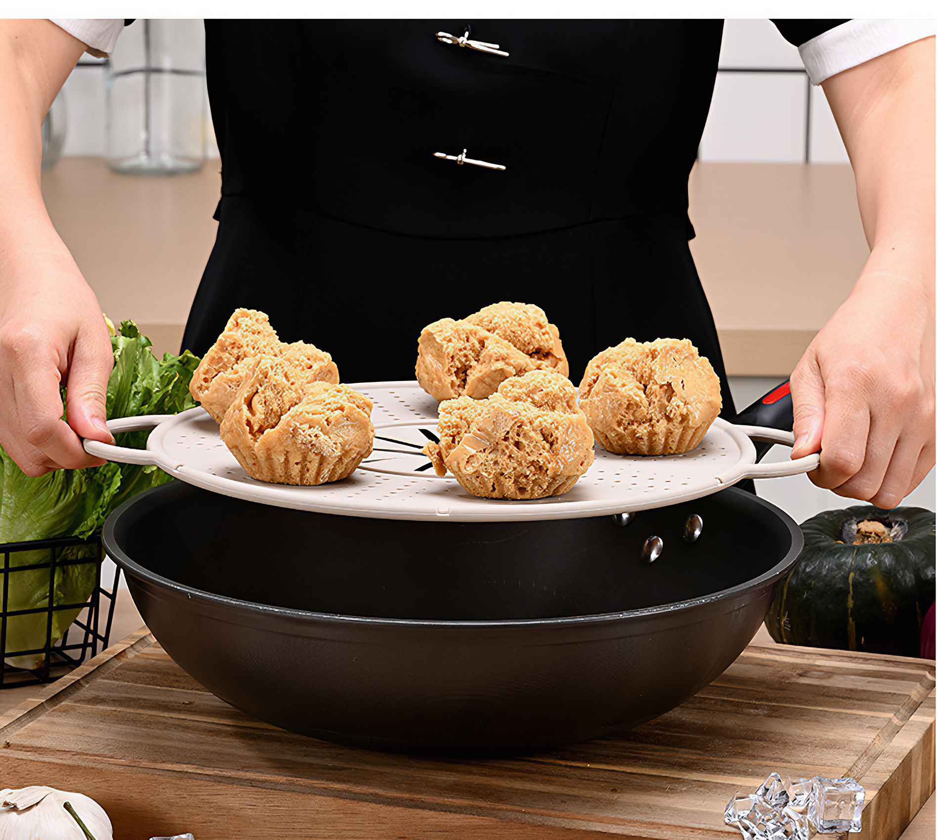 Eine Person hält ein Tablett mit gebratenen Brötchen über einem Wok. Die Szene umfasst Gemüse und ein Schneidebrett.