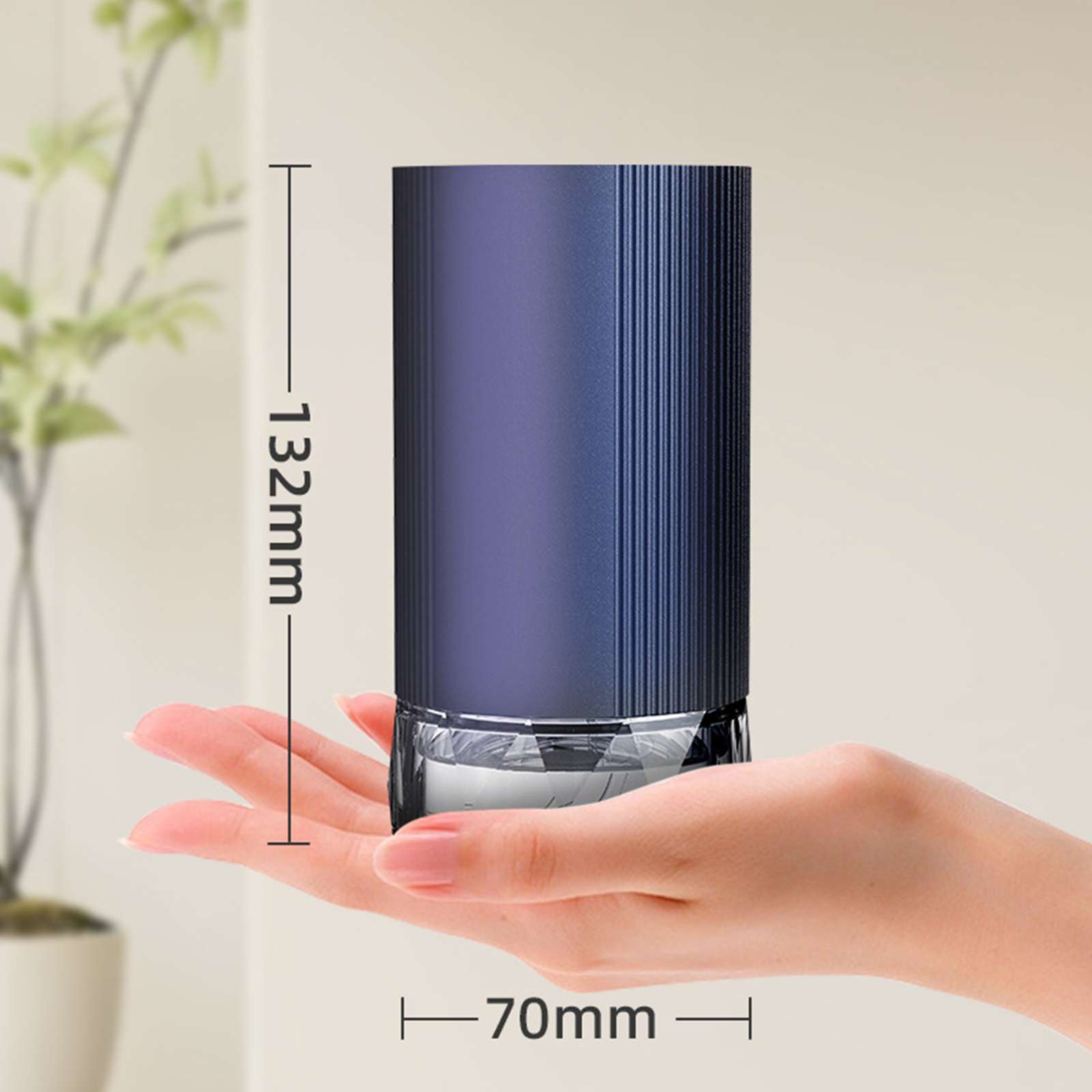 Eine Hand hält einen blauen Zylinder mit Glasbasis. Maße: 132 mm hoch und 70 mm breit. Weicher Hintergrund.