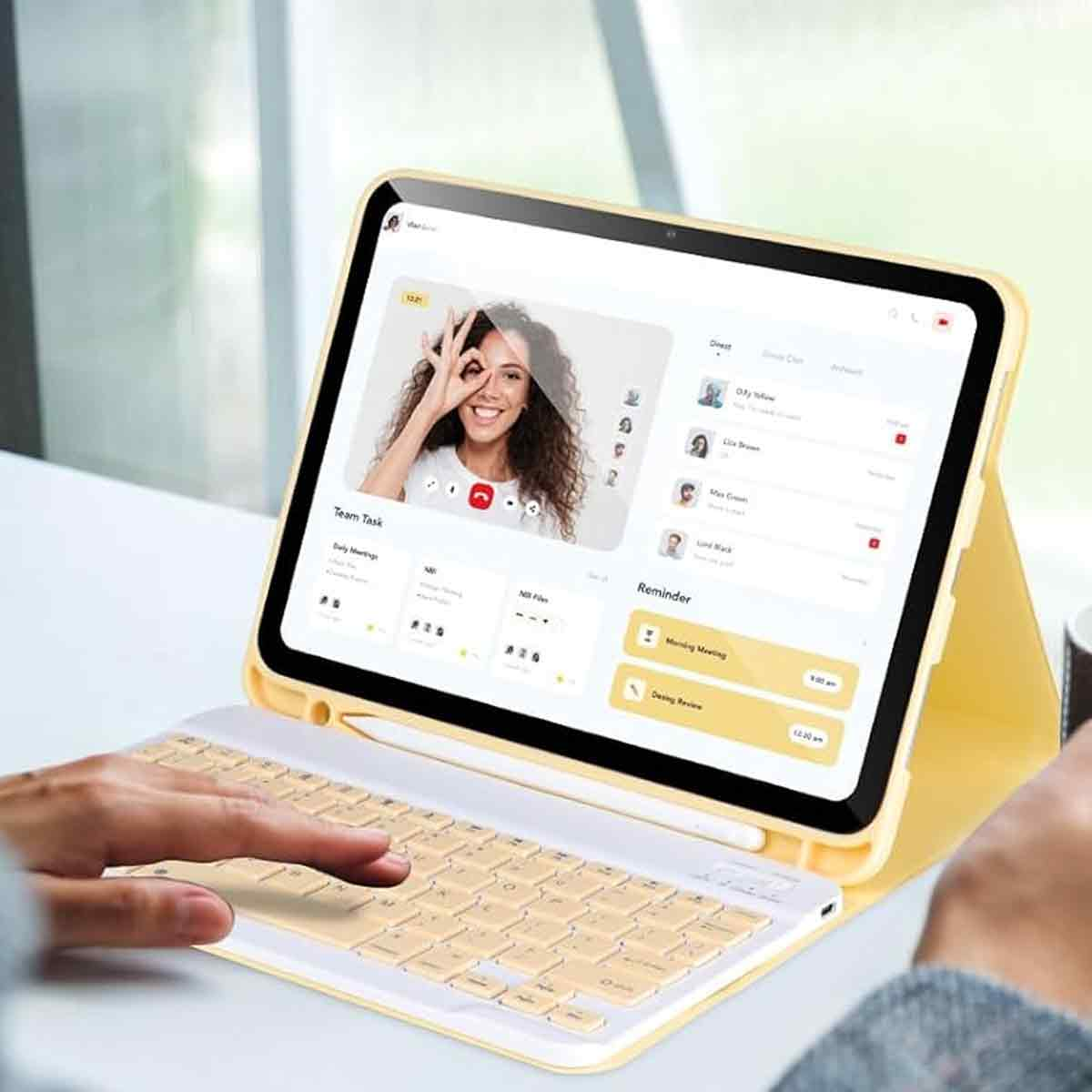 Eine Person benutzt ein gelbes Tablet mit angeschlossener Tastatur. Der Bildschirm zeigt einen Videoanruf. Eine Hand ist auf der Tastatur.