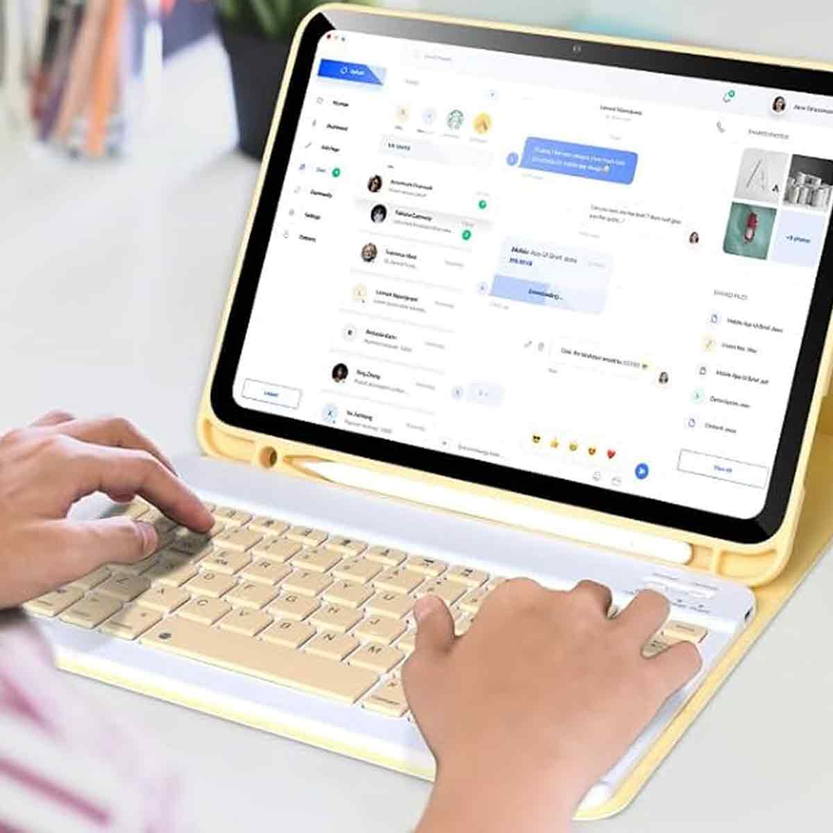Eine Person benutzt ein gelbes Tablet mit Tastatur. Der Bildschirm zeigt eine Messaging-App. Hände tippen auf der beigefarbenen Tastatur.