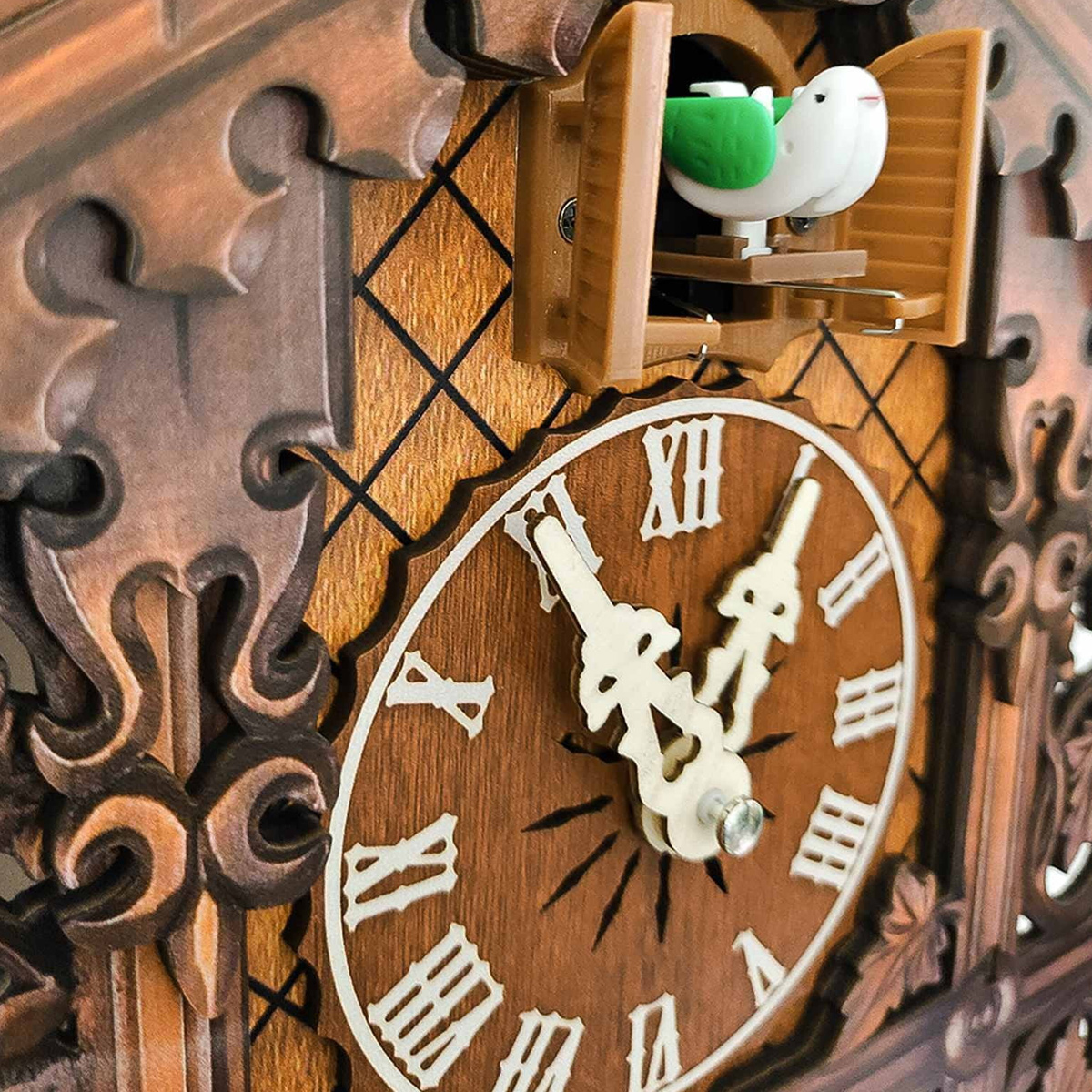 Kuckucksuhr mit weißem Vogel, grünen Flügeln und römischen Ziffern. Die Uhr ist aus Holz und hat dekorative Schnitzereien.